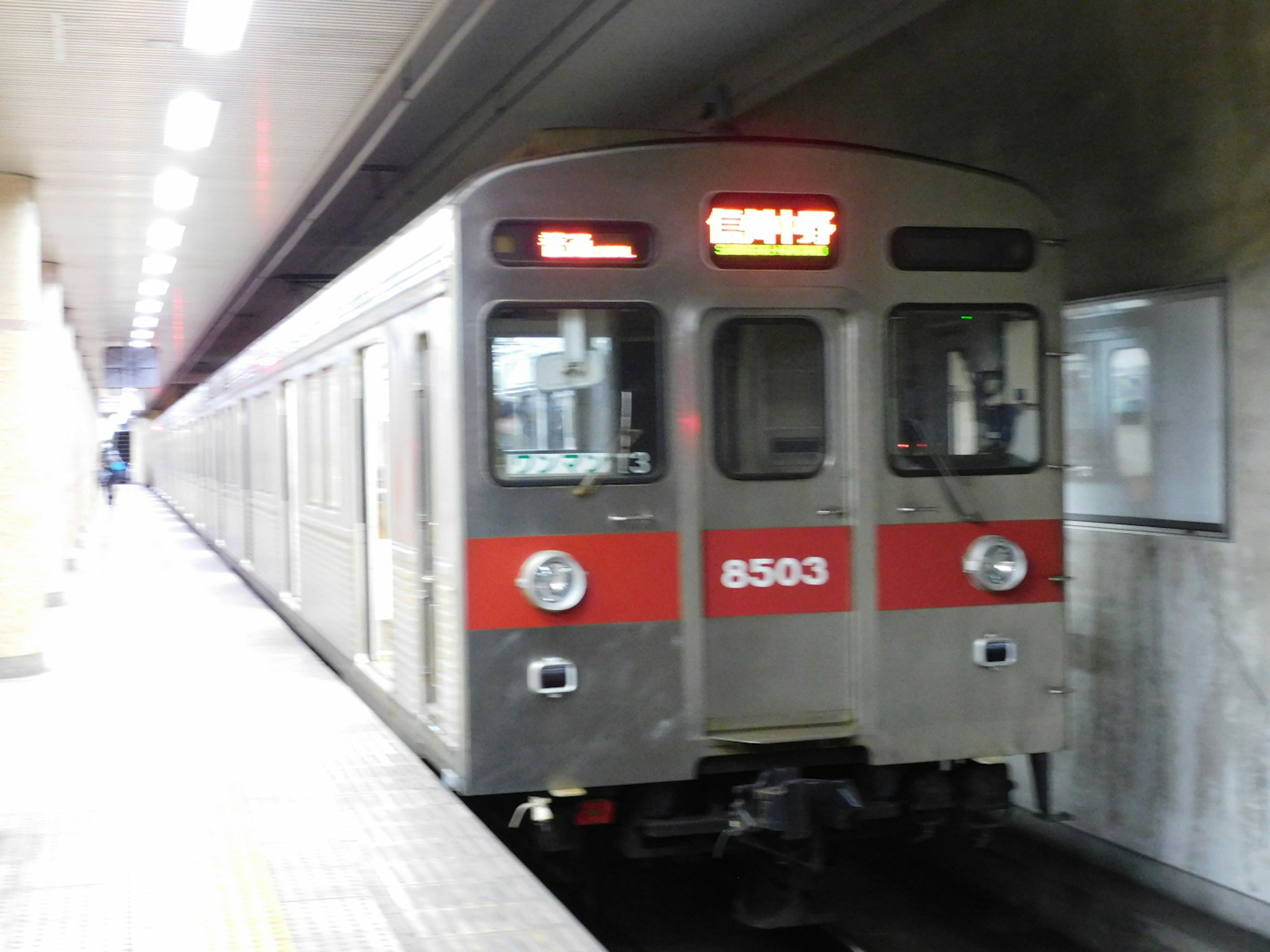 Silver subway train with red stripes stopped at the station