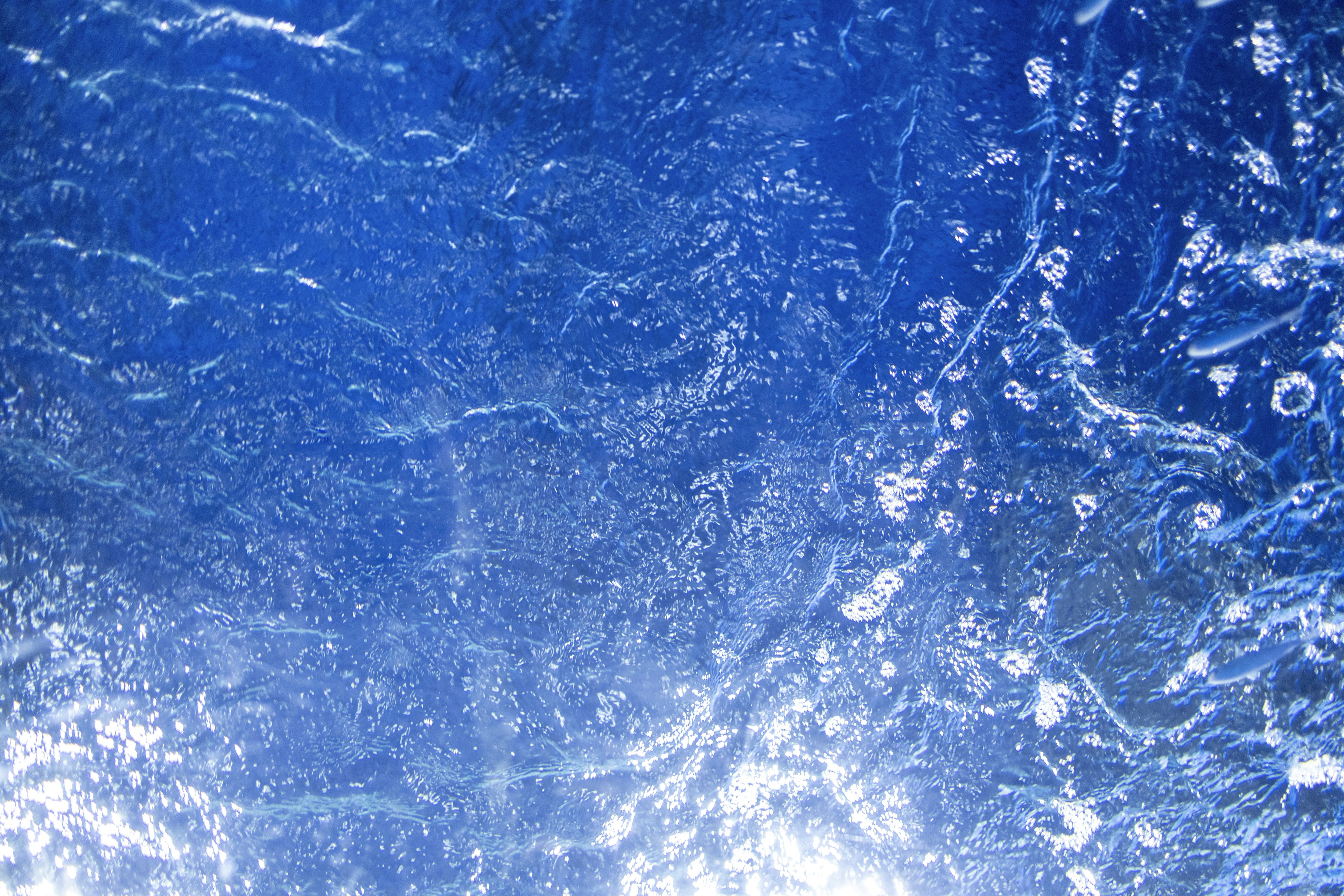 Surface of blue water showing bubbles and ripples