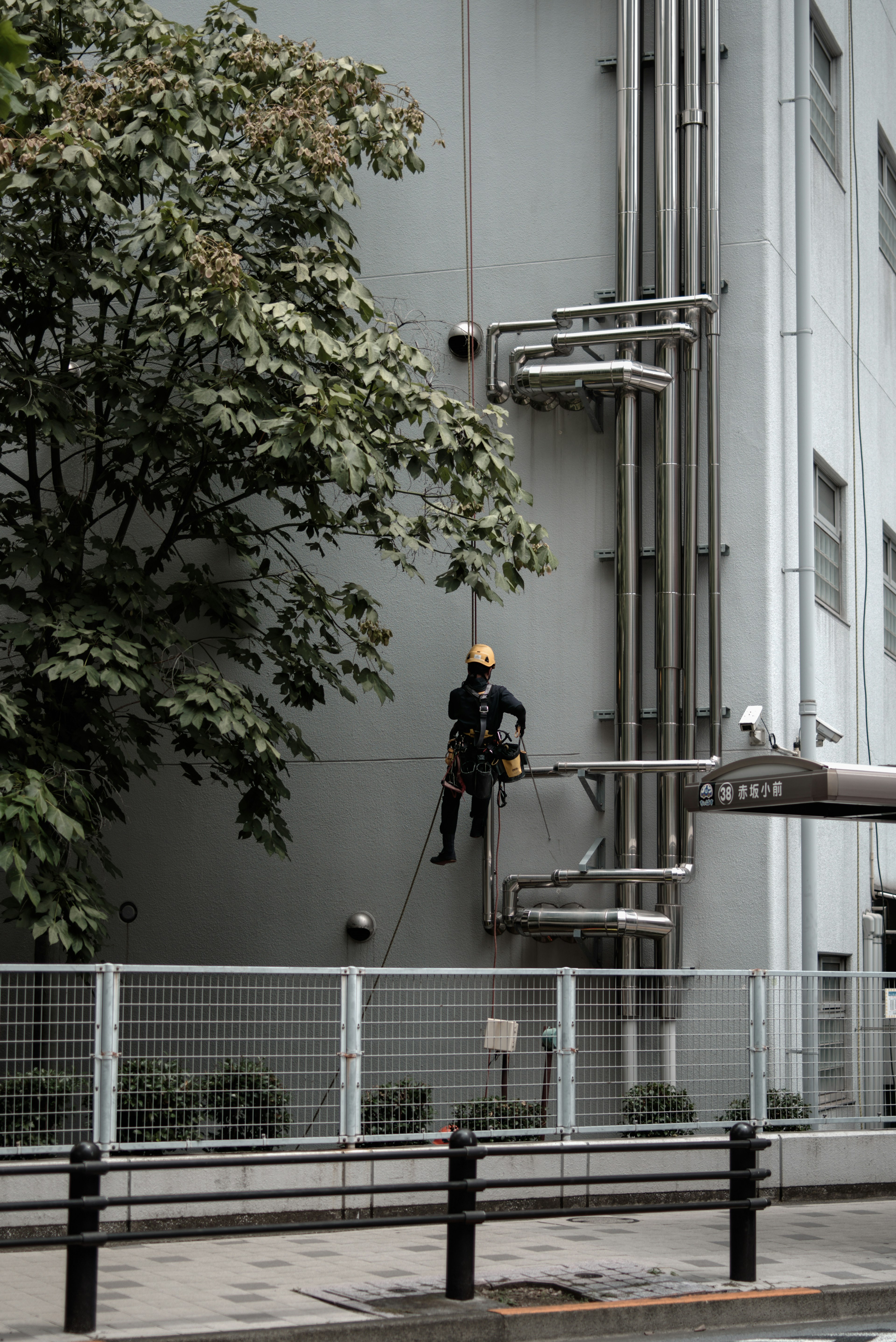 Worker performing high-rise maintenance on a gray building wall