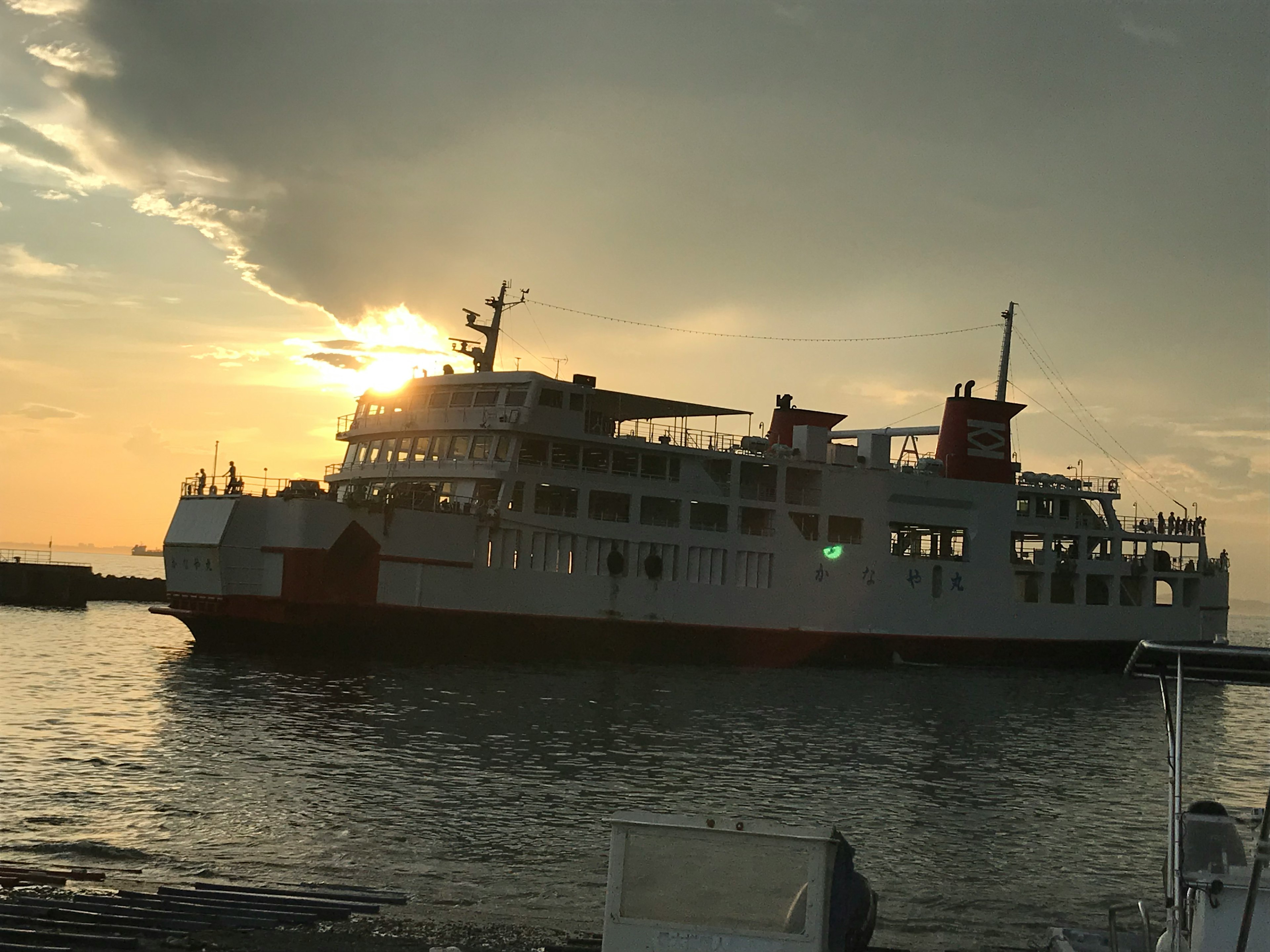 A ferry docked at the port against a sunset backdrop