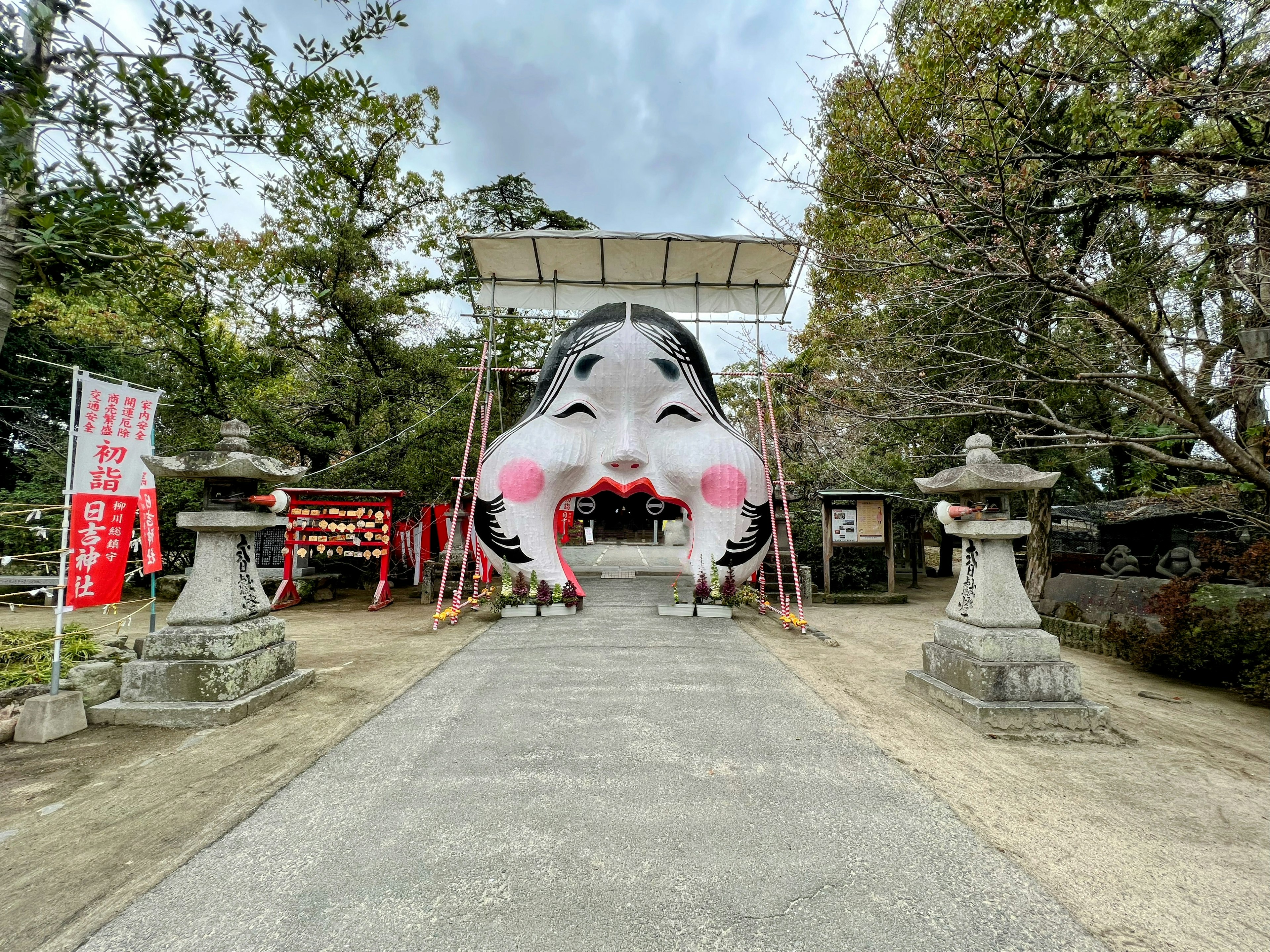 神社入口处的大型装饰性面孔结构，具有独特的红色脸颊