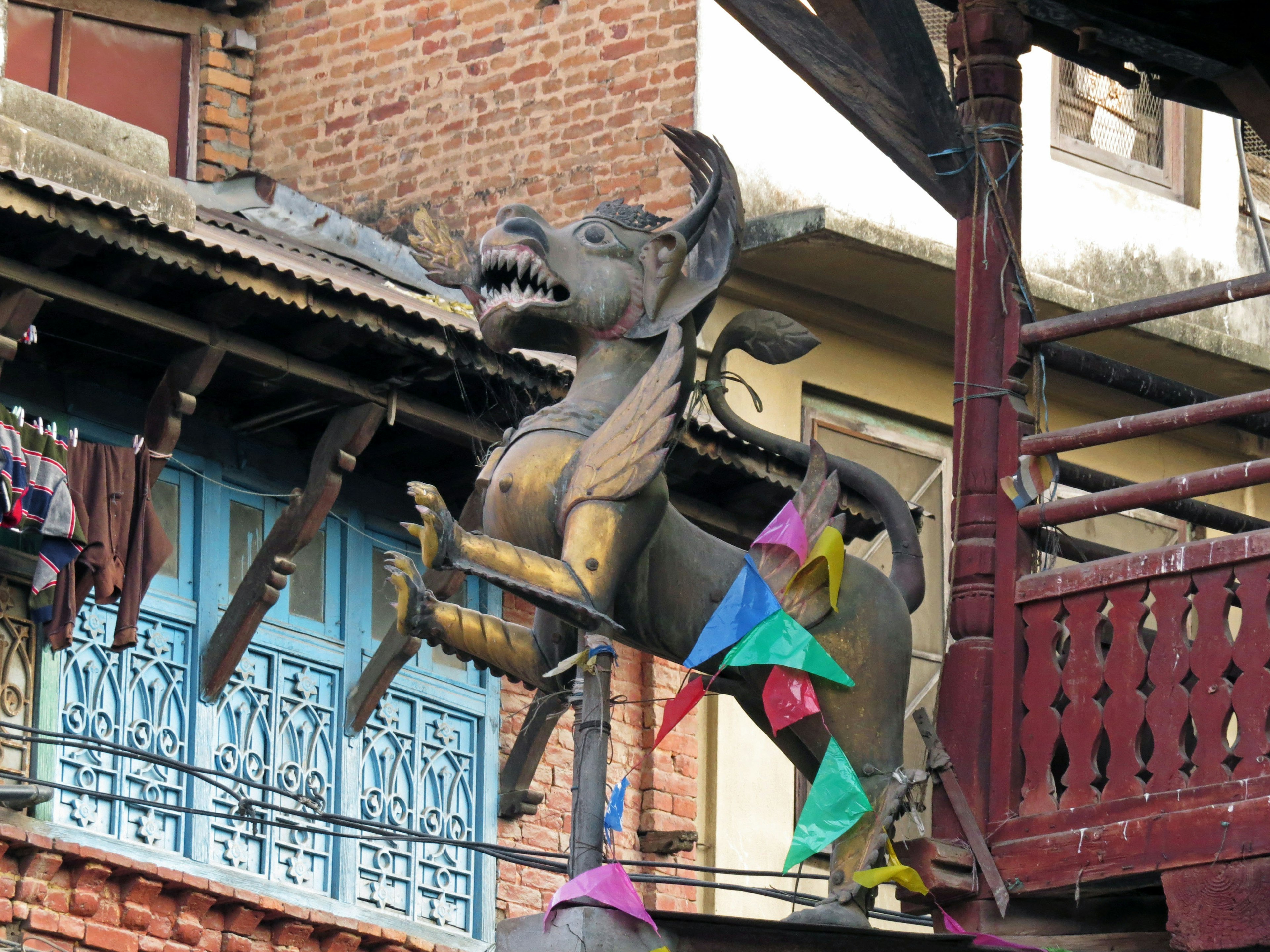 Dragon sculpture atop a building with colorful fabric decorations