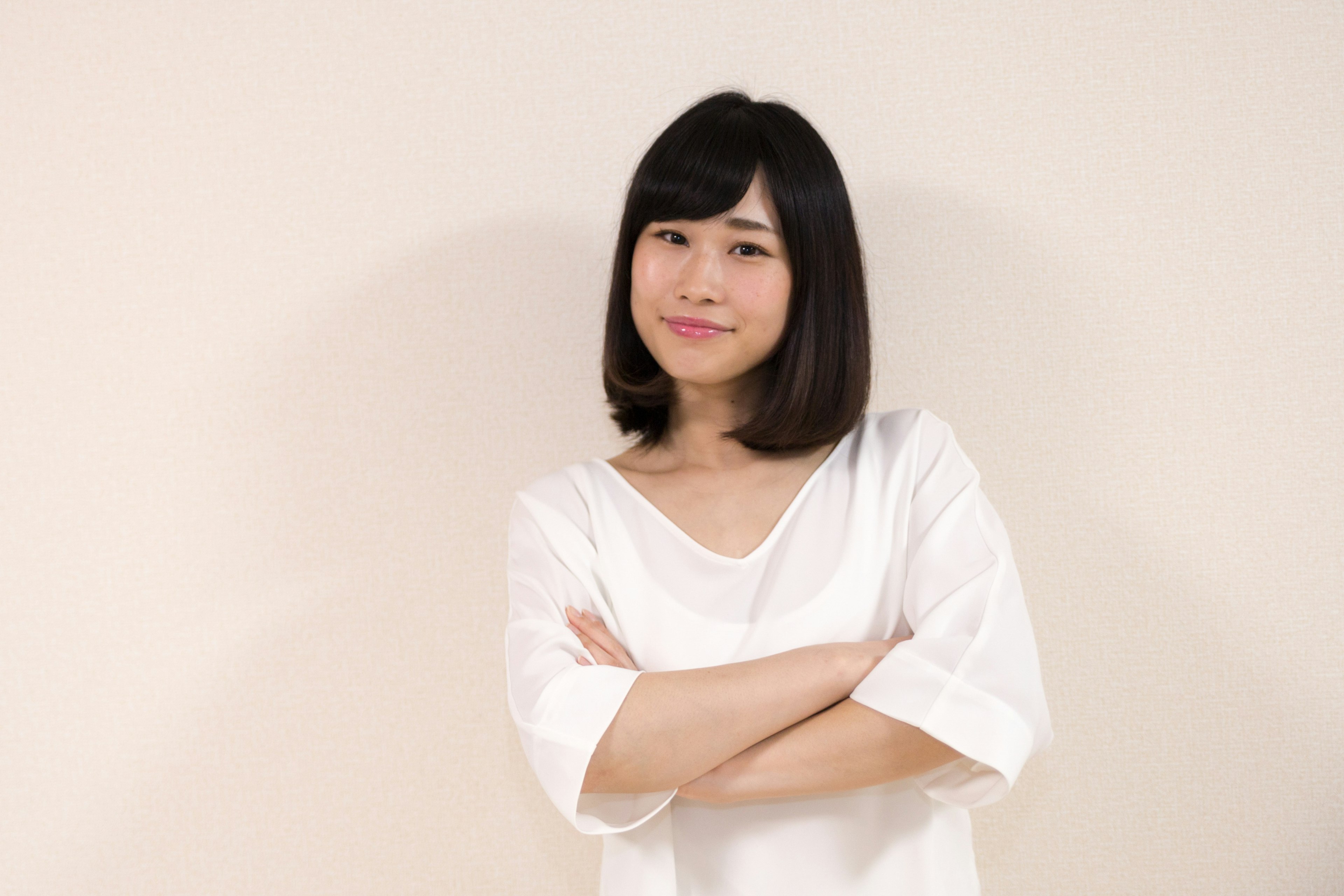 Woman in white shirt smiling with arms crossed