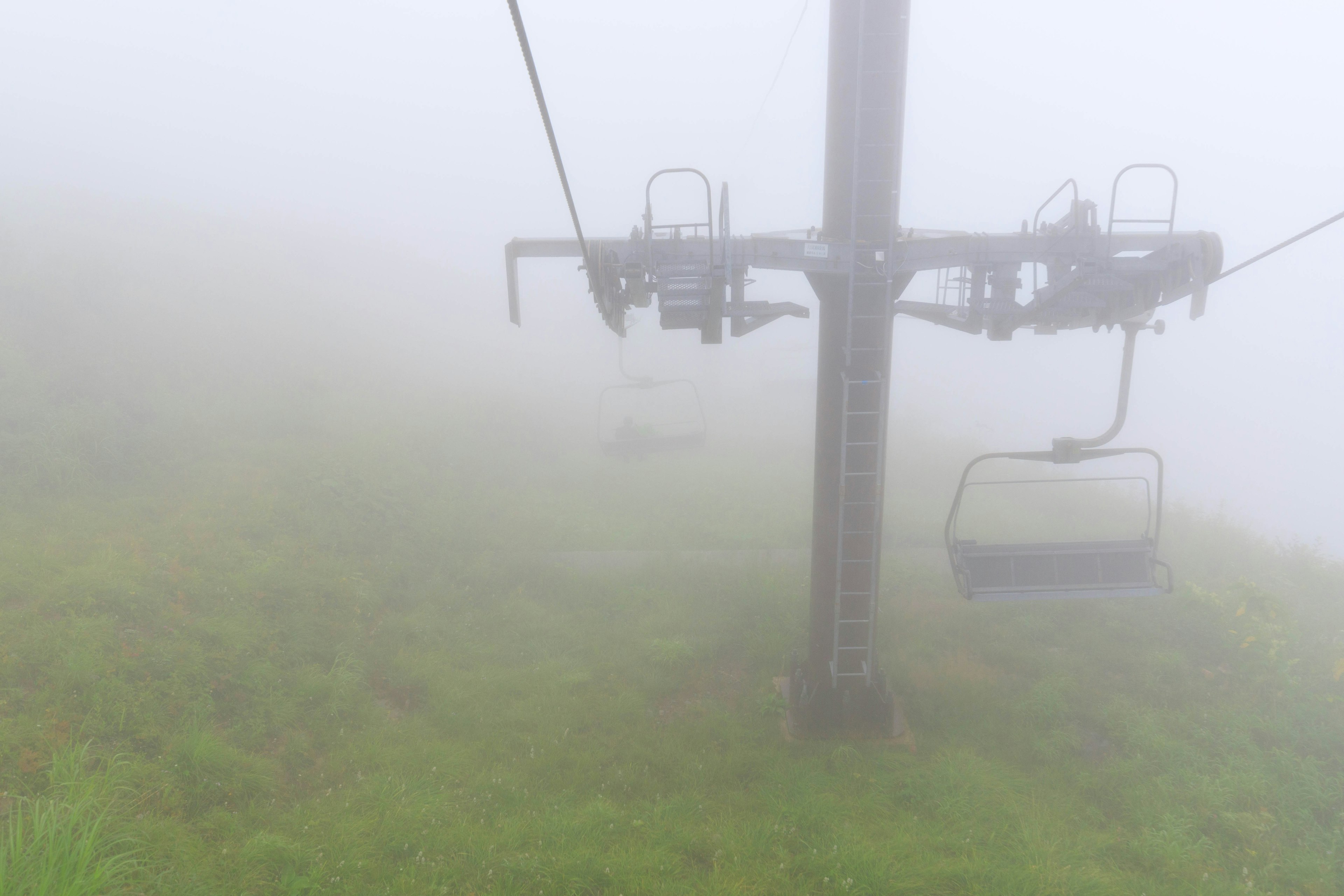 Skilift-Turm und Sitze in einer nebligen Landschaft