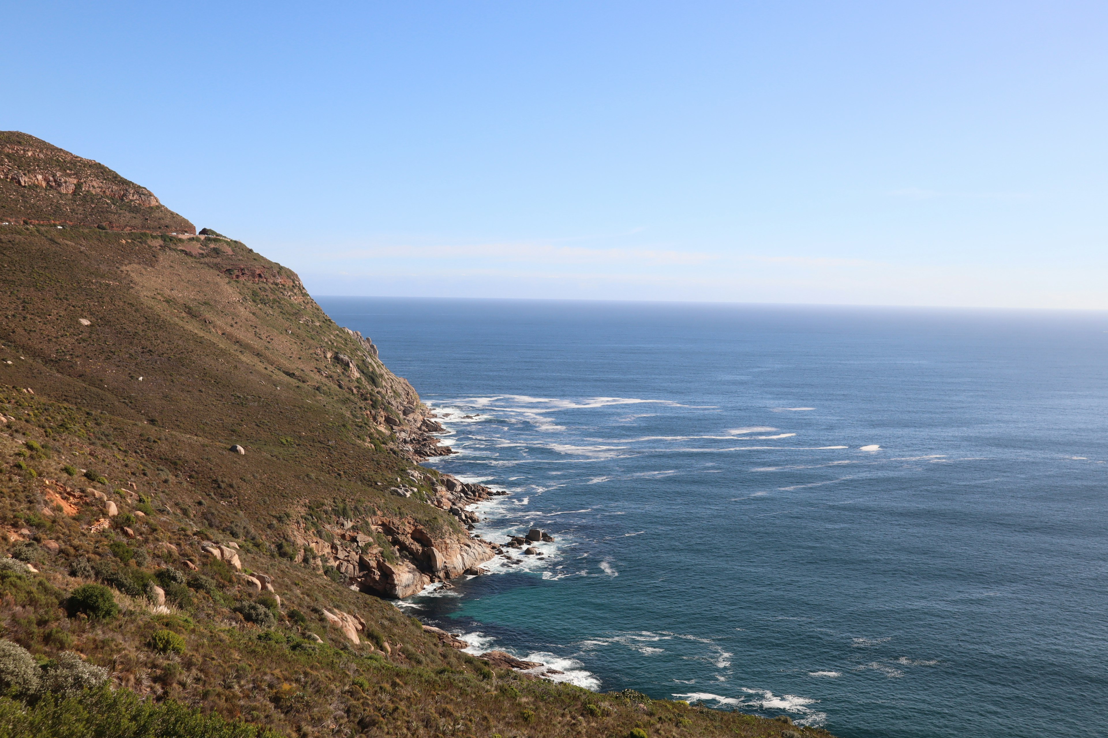 Vista escénica del océano y la colina con cielo azul claro y olas