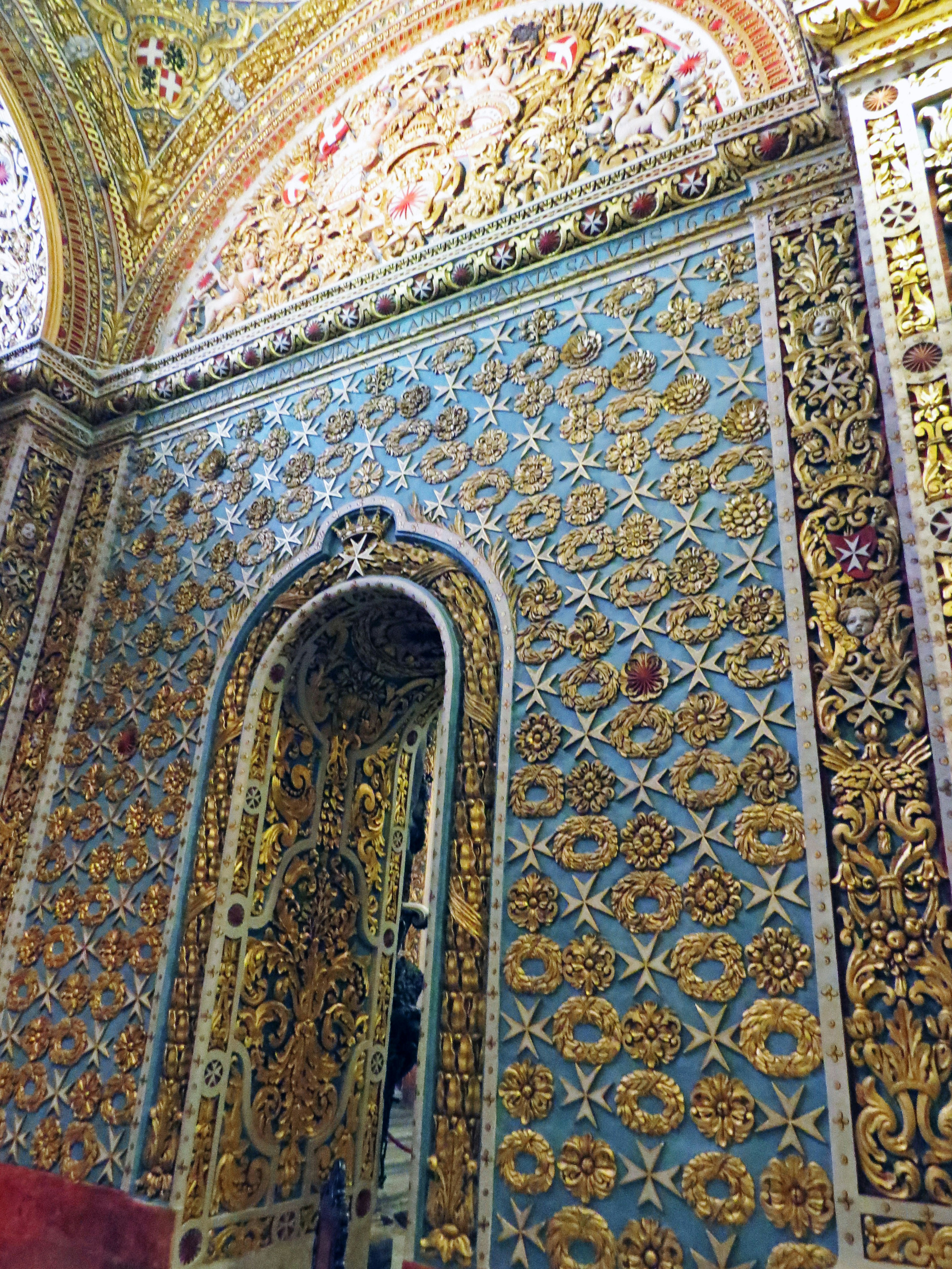 Ornately decorated wall featuring intricate patterns and an arched doorway