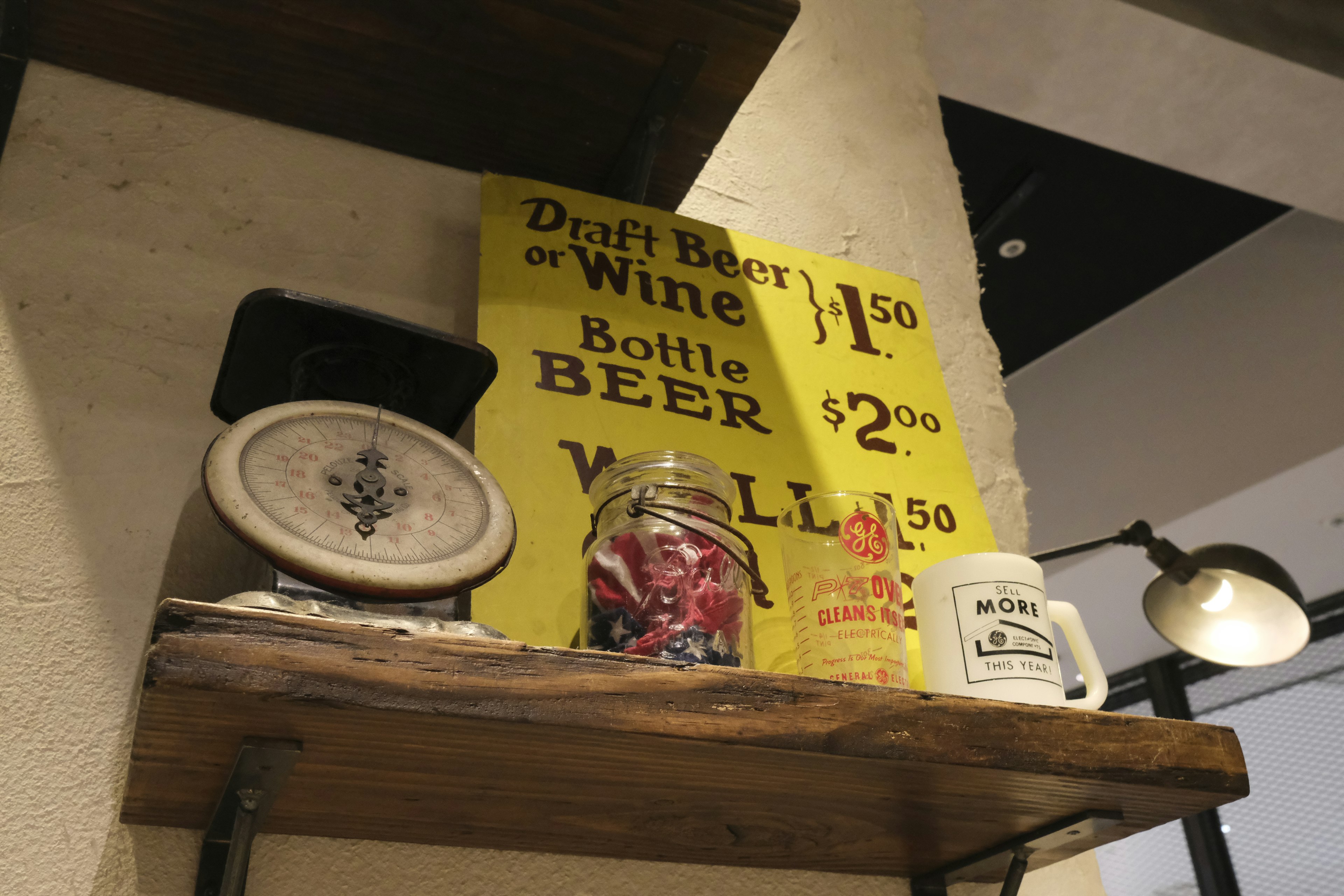 Vintage sign and drink containers displayed on a wooden shelf