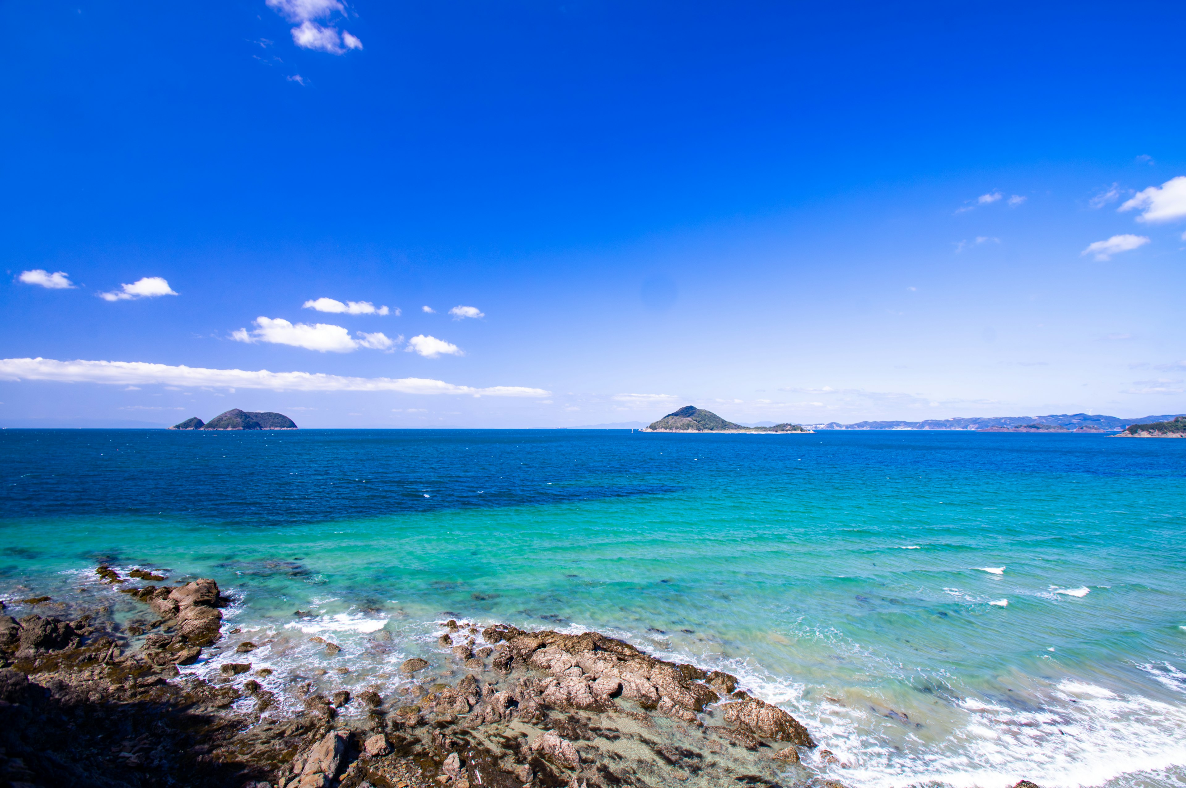 Malersiche Aussicht auf das blaue Meer und die felsige Küste klarer Himmel mit weißen Wolken