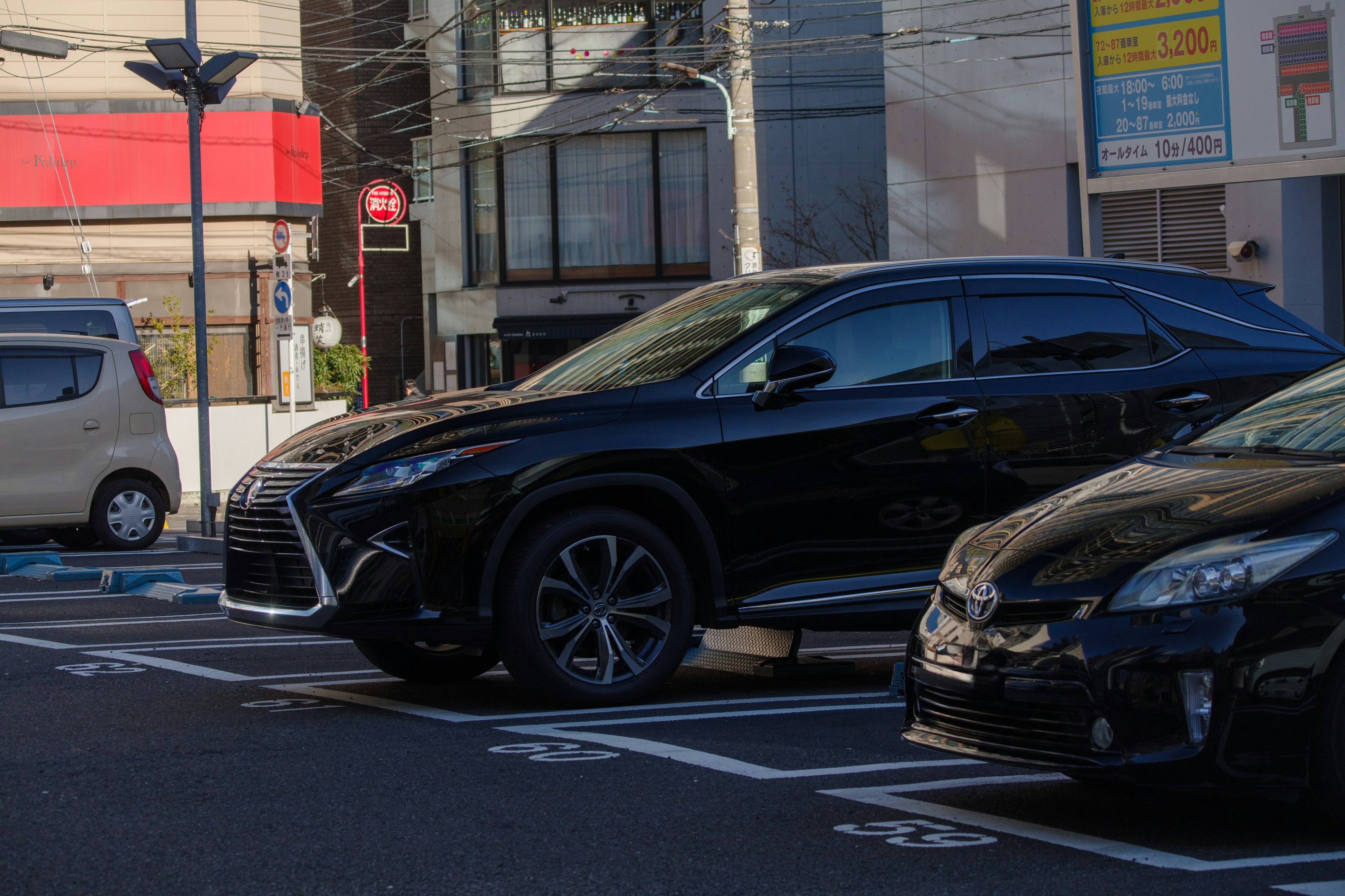 Image d'une Lexus noire garée à côté d'autres véhicules dans un parking