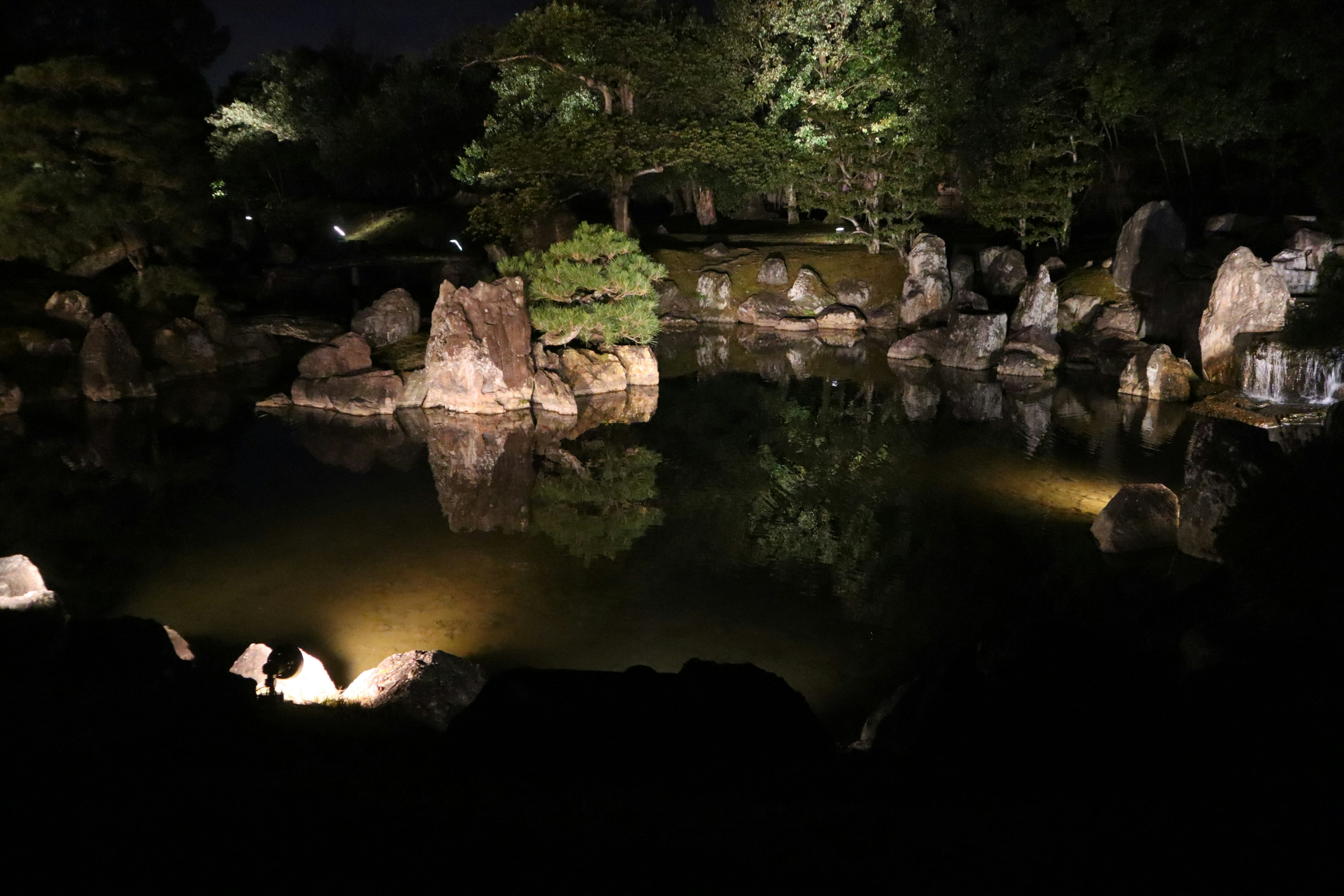 Luz suave iluminando un estanque y rocas por la noche