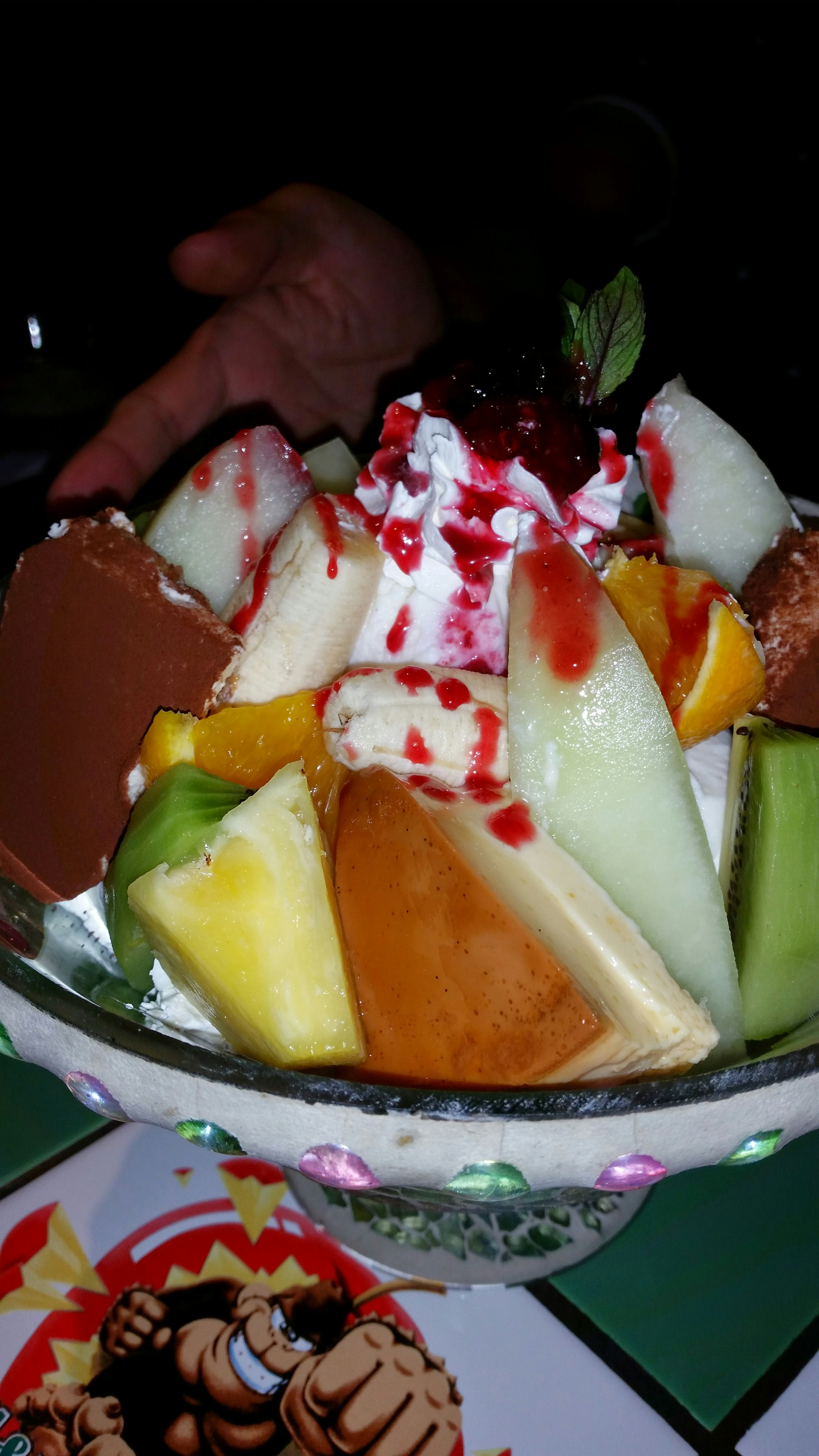 Colorful dessert bowl filled with various fruits and ice cream