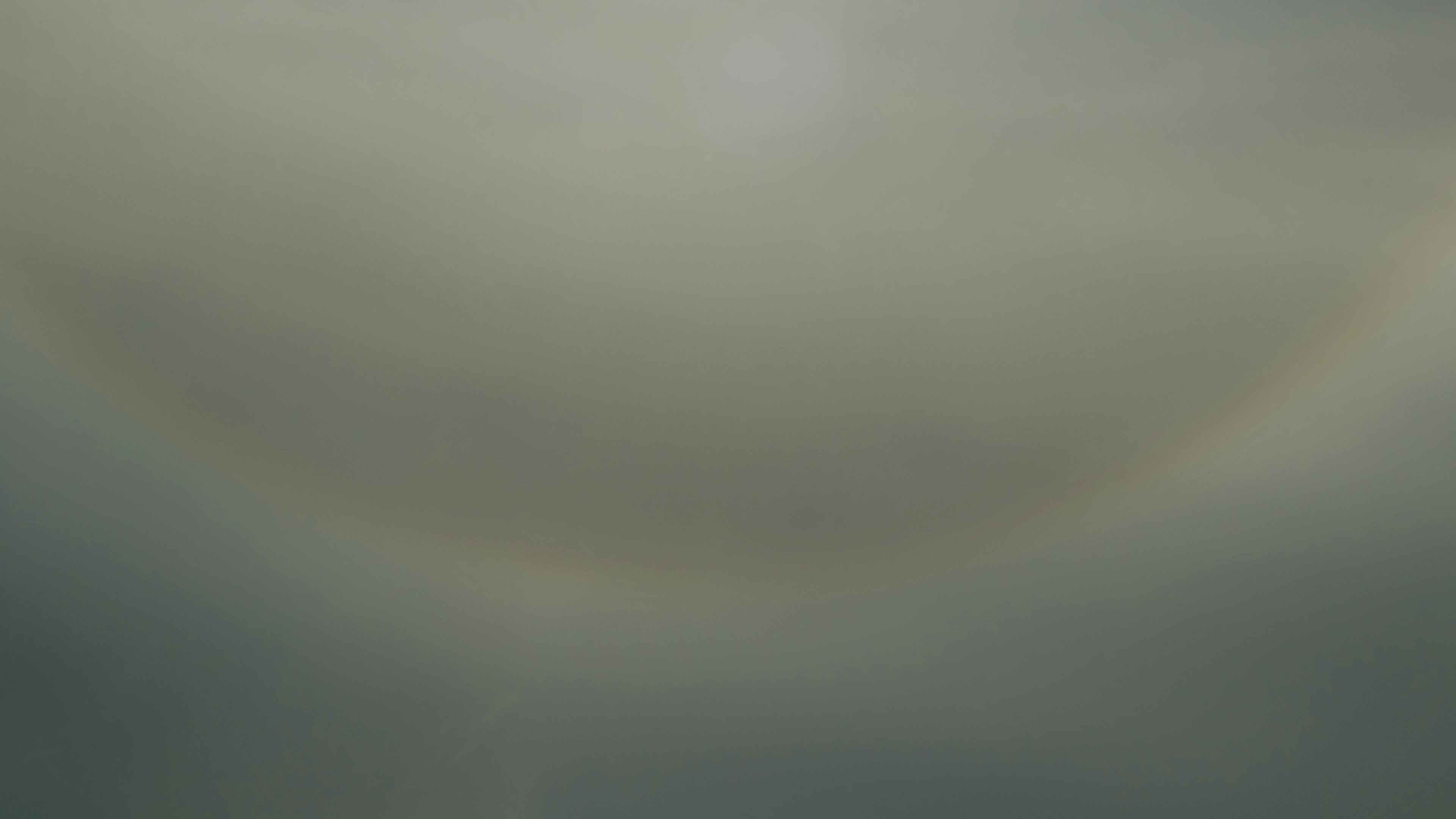 A soft rainbow arching across a cloudy sky