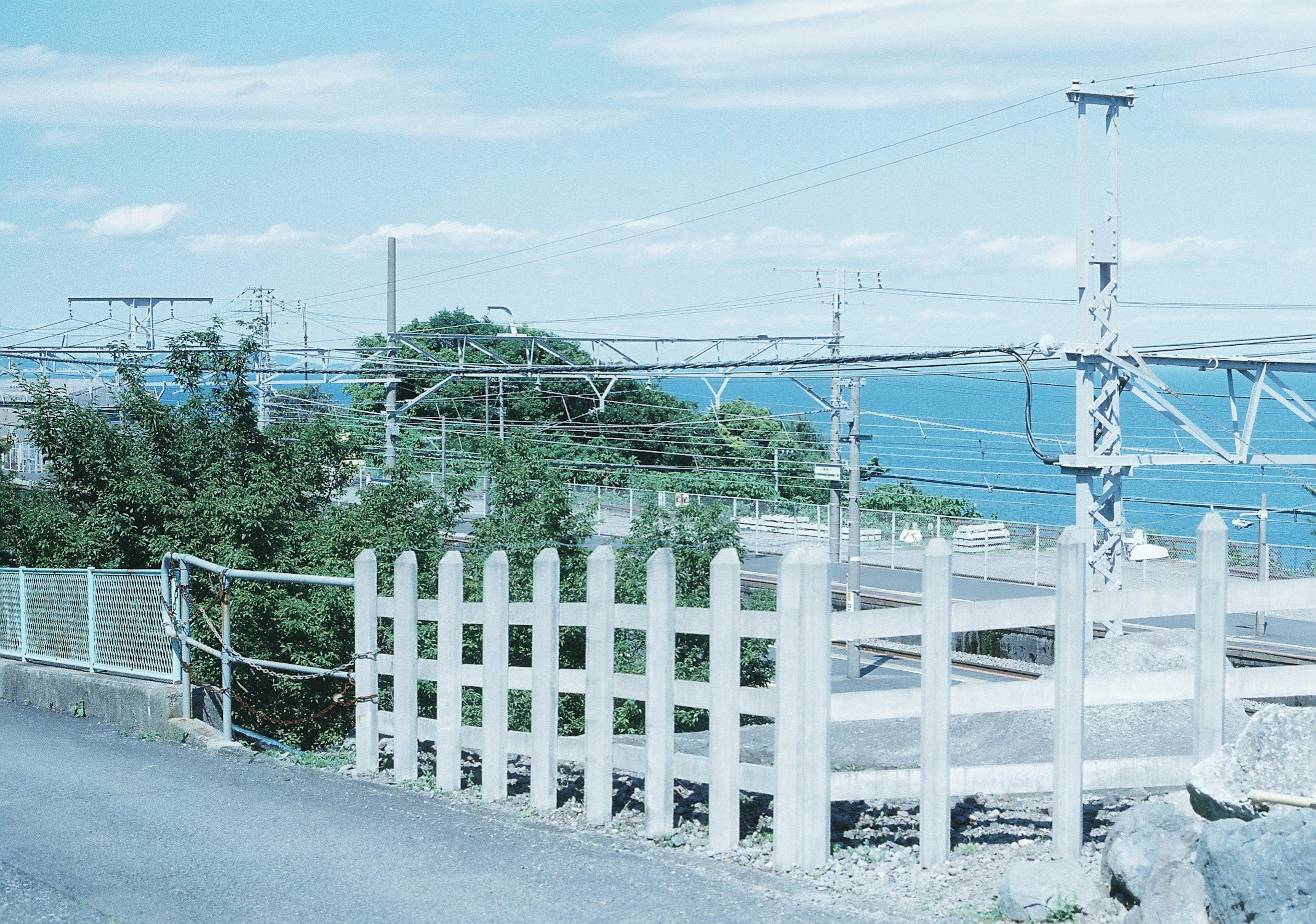 青い海と空を背景にした鉄道のフェンスと電線の風景