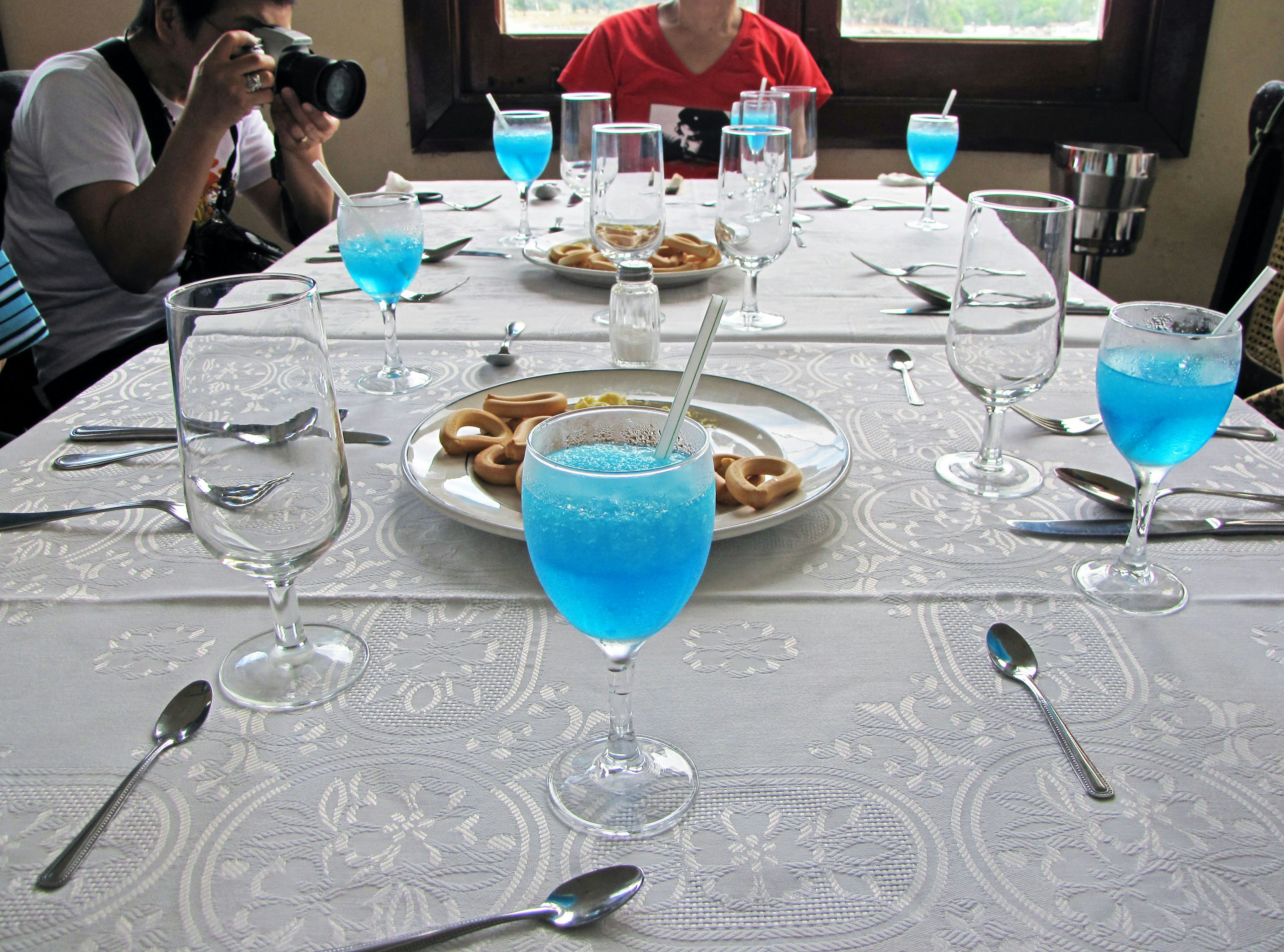 Tisch mit blauen Getränken und Snacks umgeben von Menschen