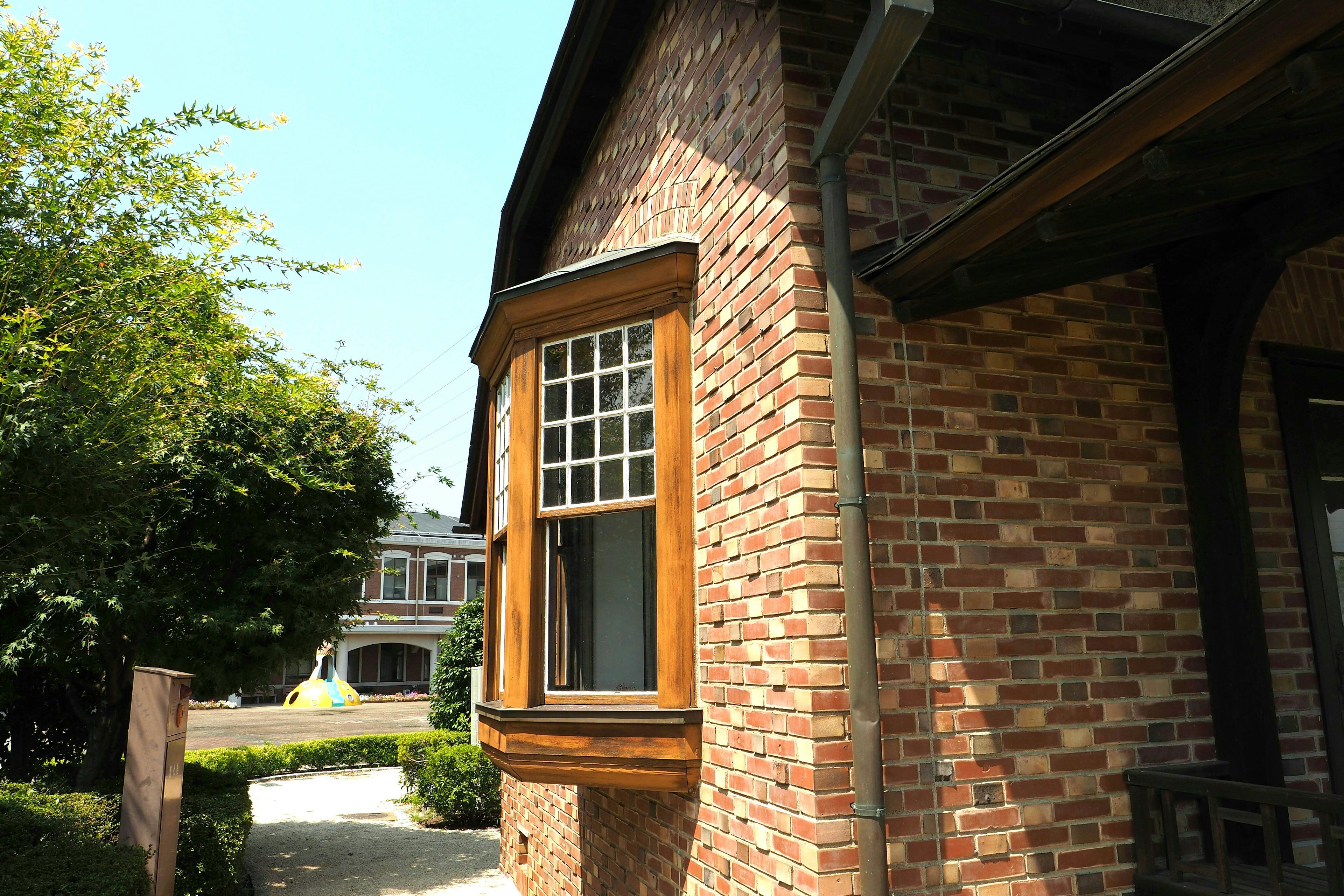 Eckansicht eines Backsteinhauses mit einem Holzfenster und üppigem Grün