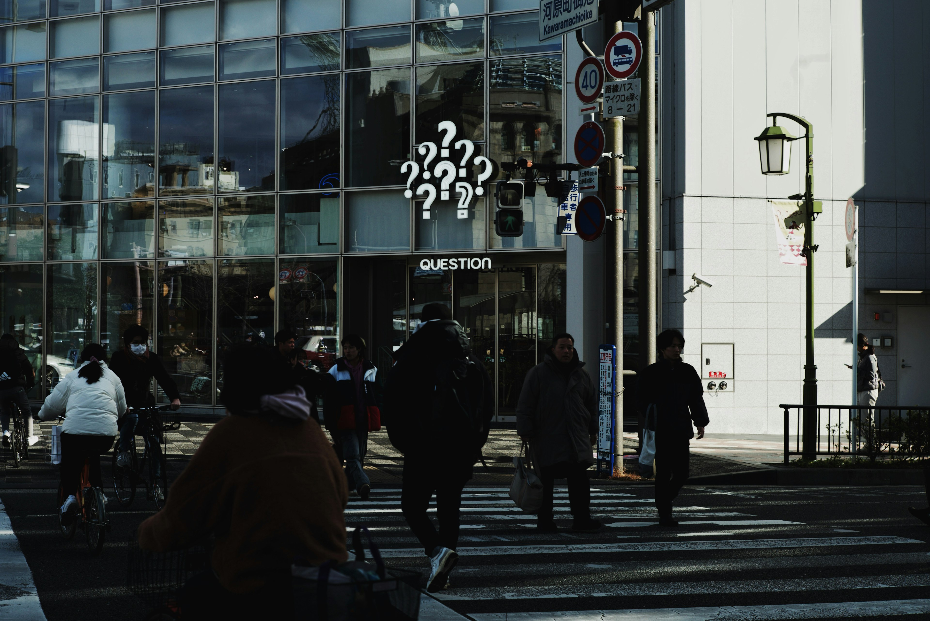 People crossing the street with a building featuring a 'QUESTION' sign