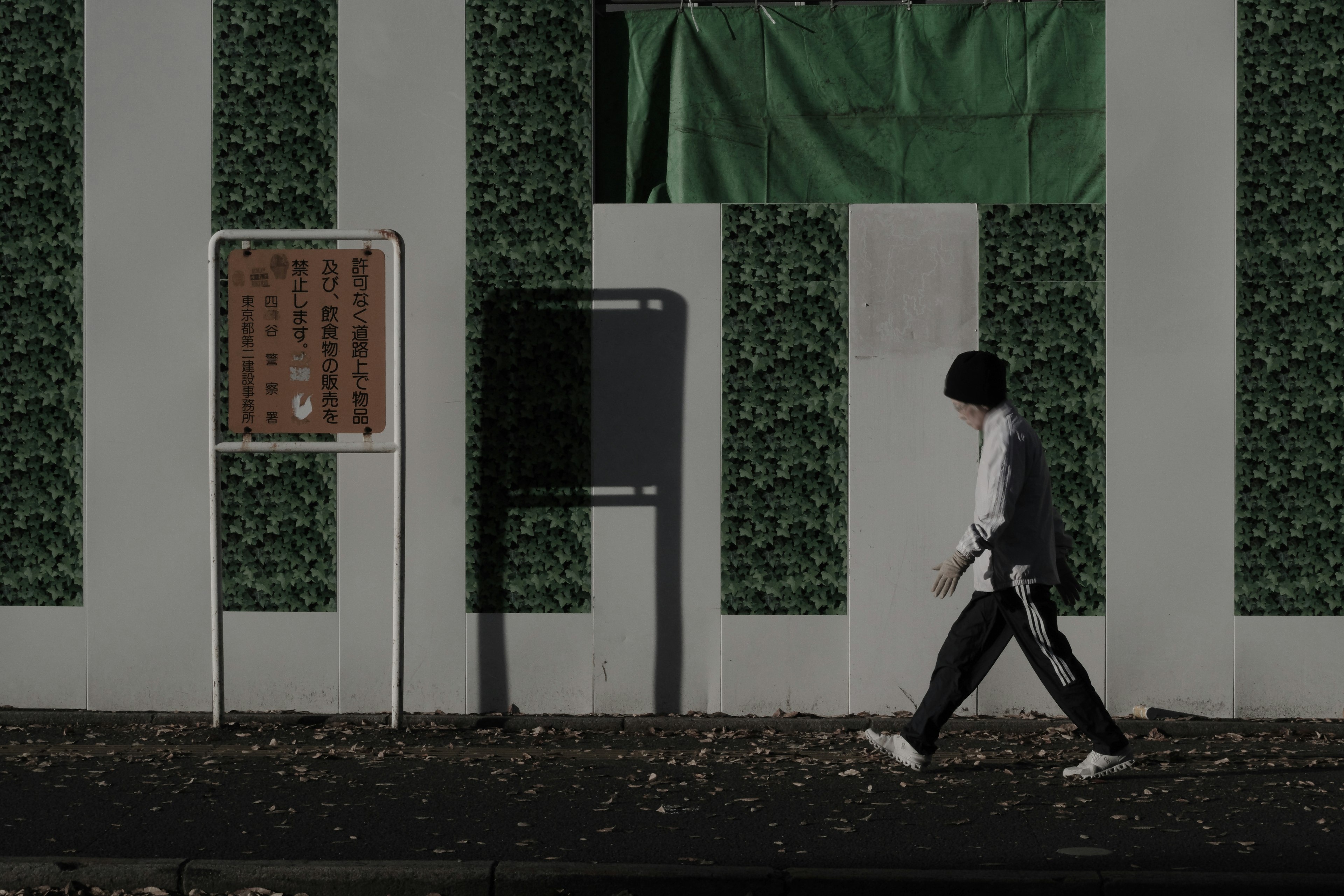 一個人在城市環境中走在綠色牆壁和標誌前面