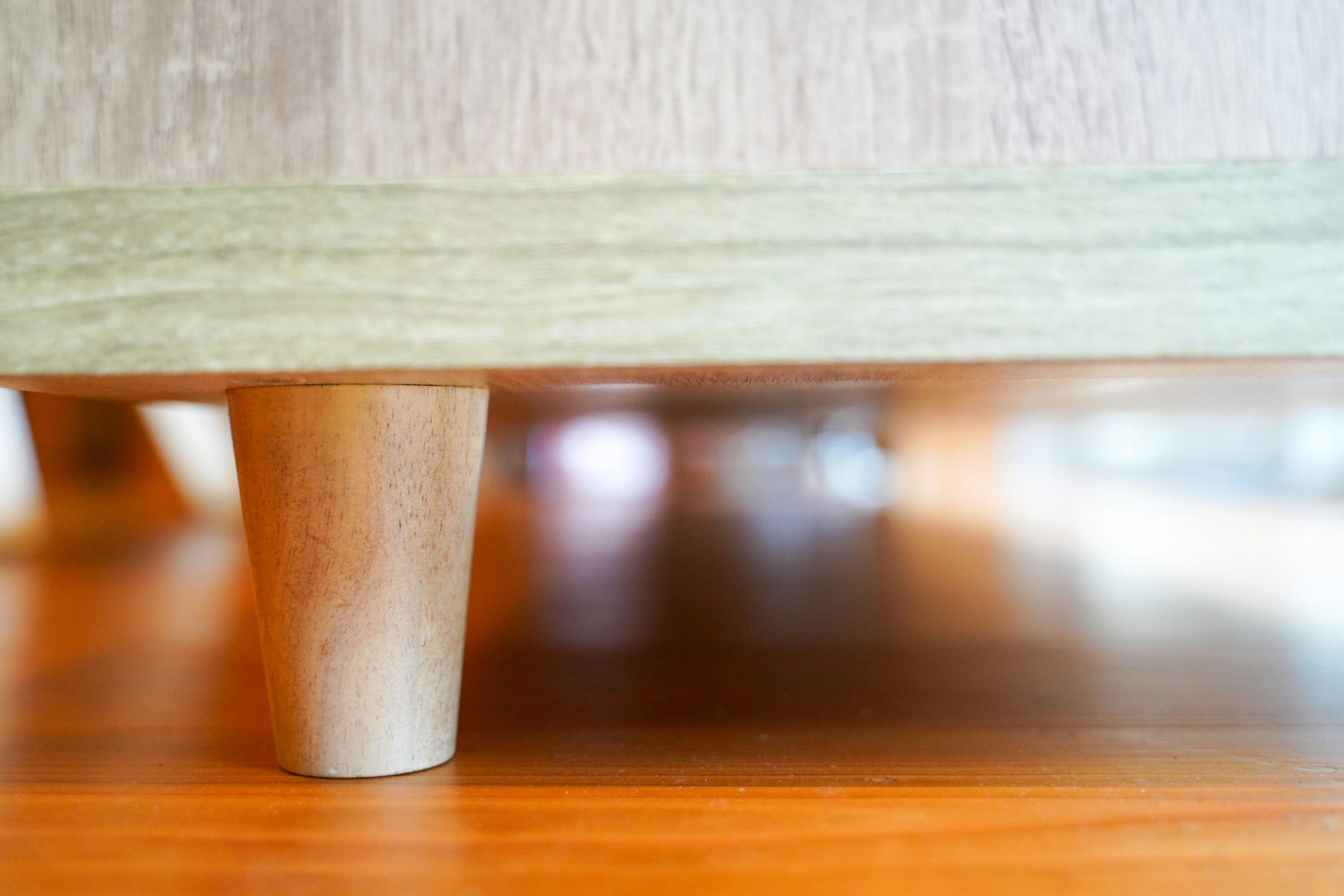 Close-up of a wooden table leg on a bright wooden floor