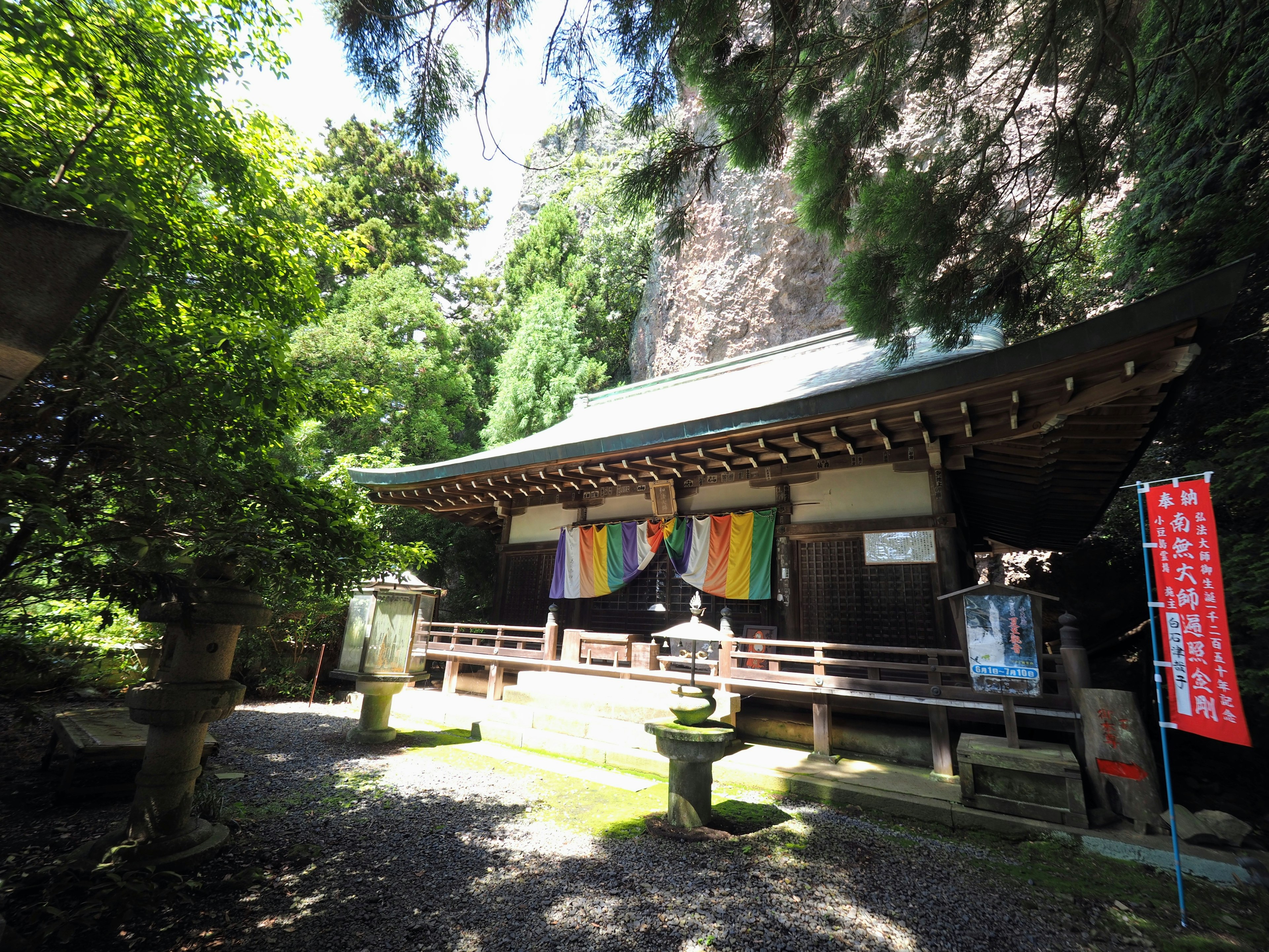 传统日本寺庙被绿色植物包围，悬挂着彩色布料