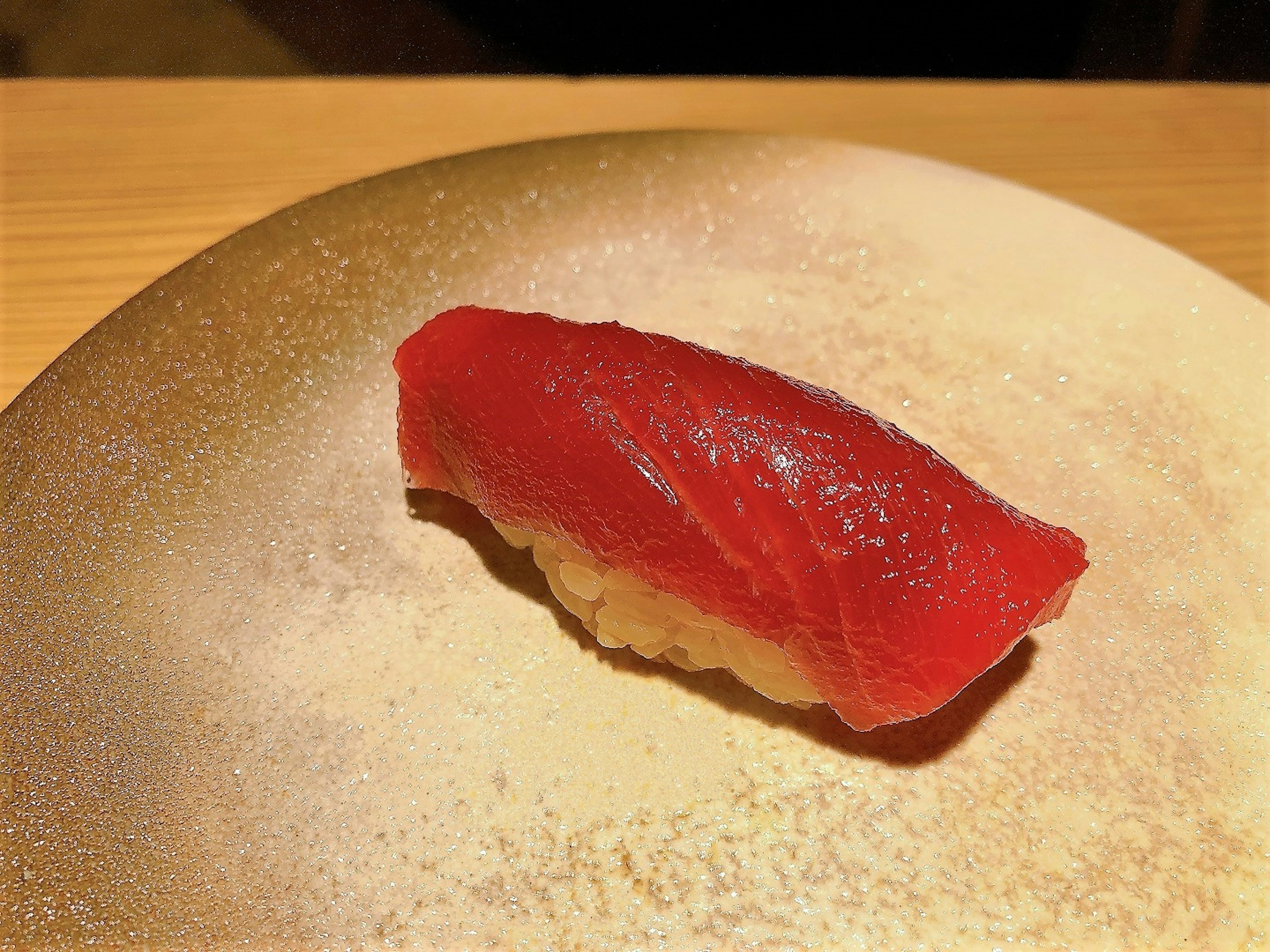 A piece of red tuna sushi on a golden plate