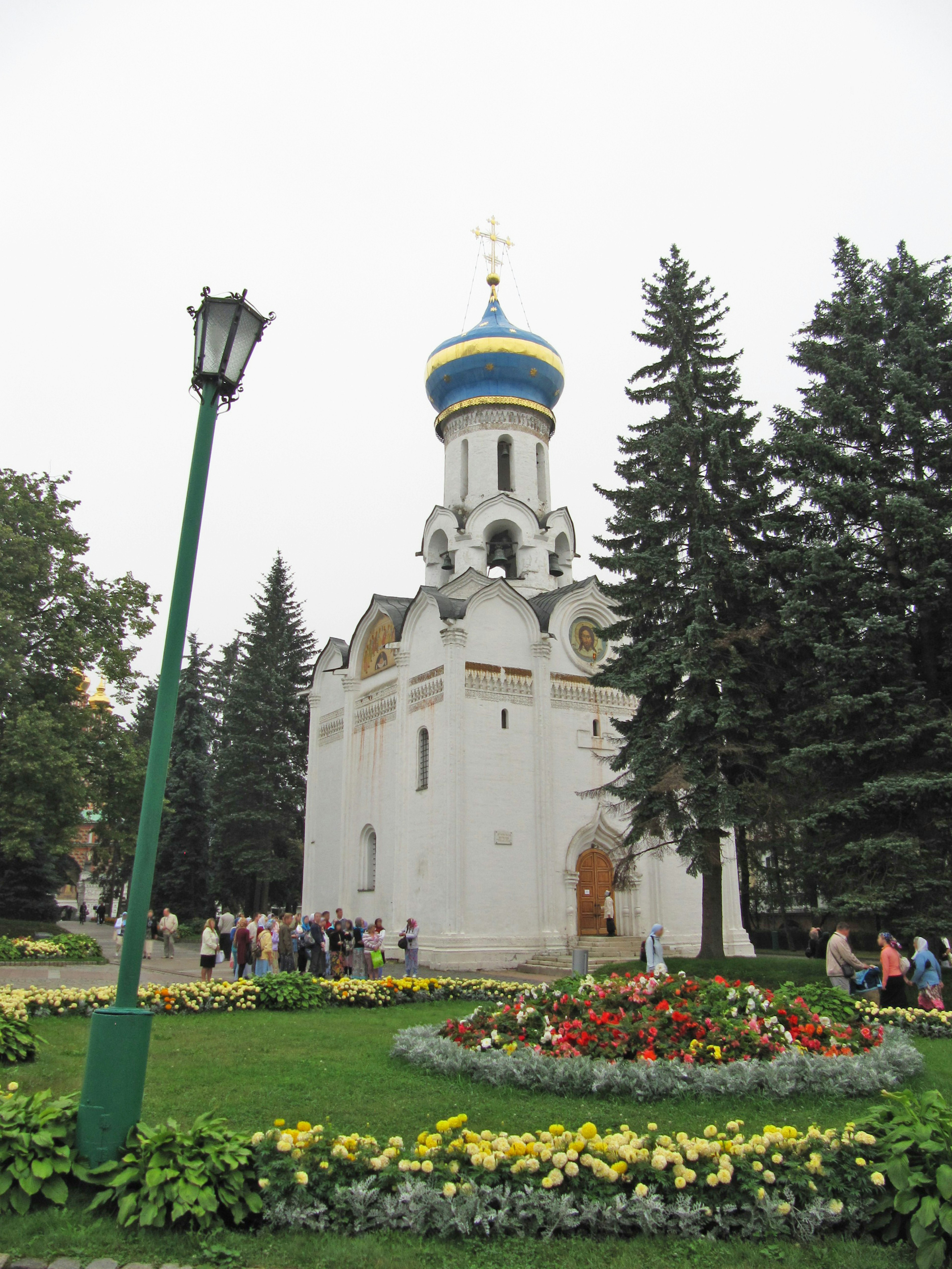 White church with blue dome surrounded by colorful flower beds