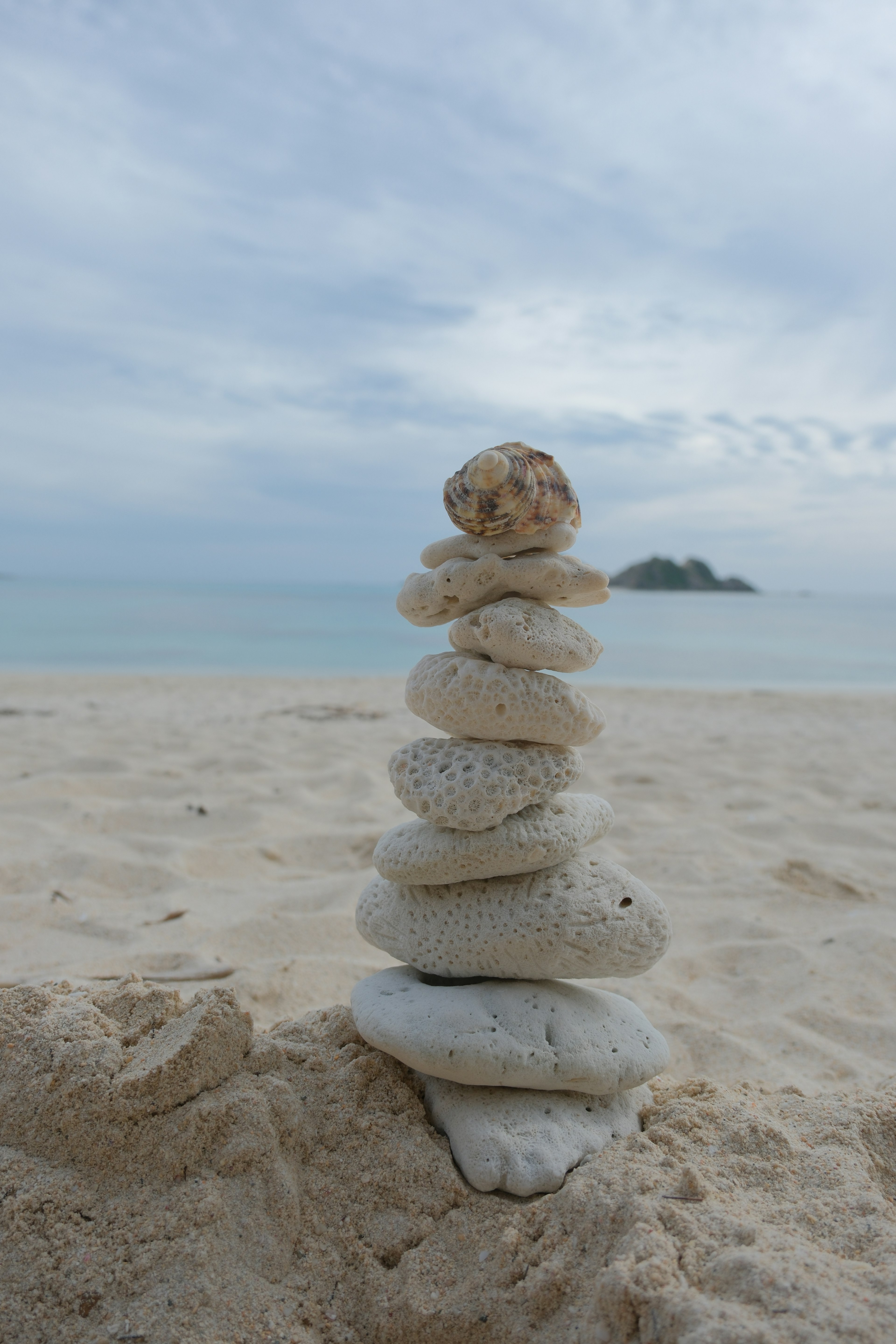 Stapel aus glatten Steinen am Strand mit ruhigem Meer im Hintergrund