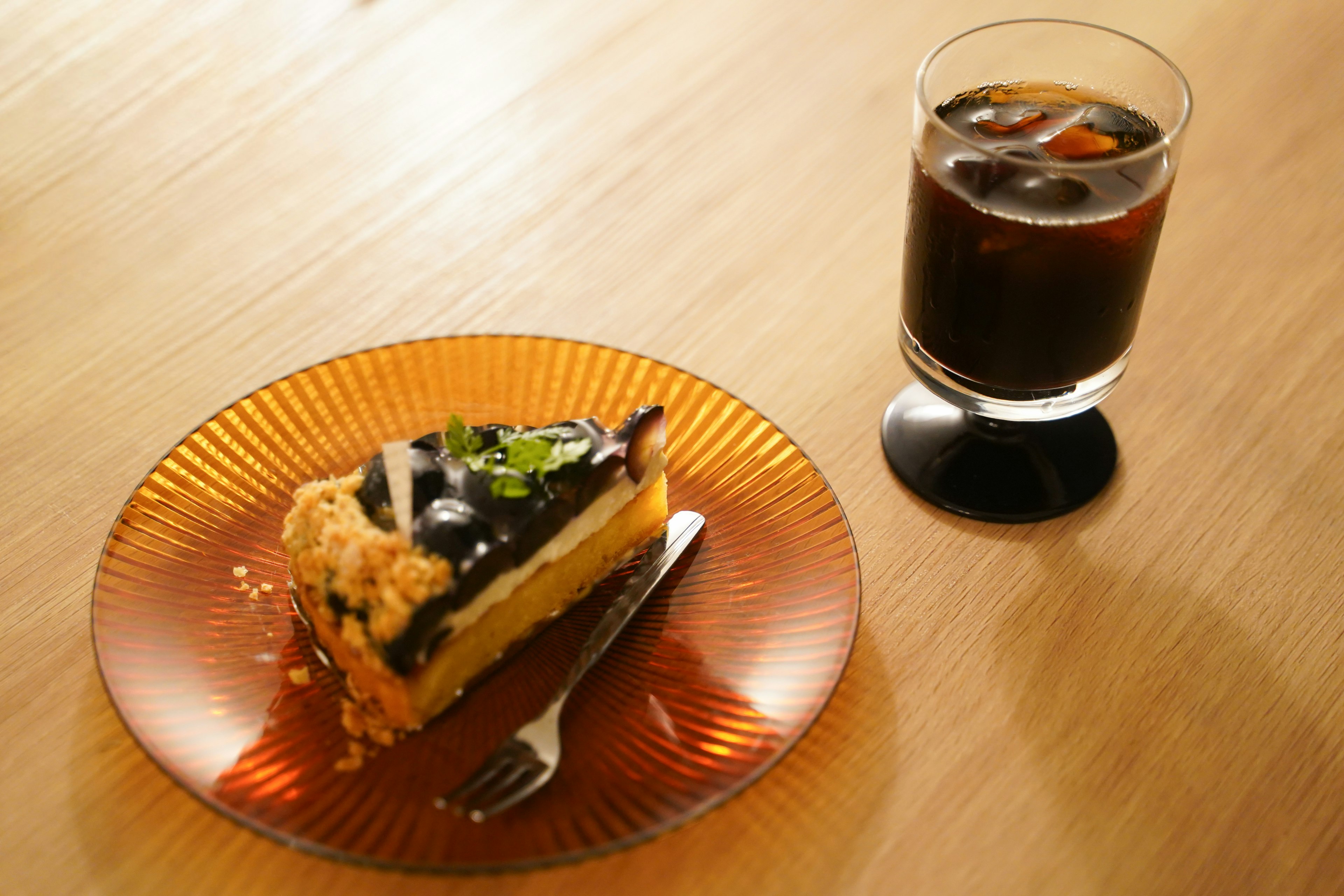 美しいケーキと飲み物の写真 ケーキはチョコレートとフルーツのトッピング 飲み物はグラスの中のアイスコーヒー