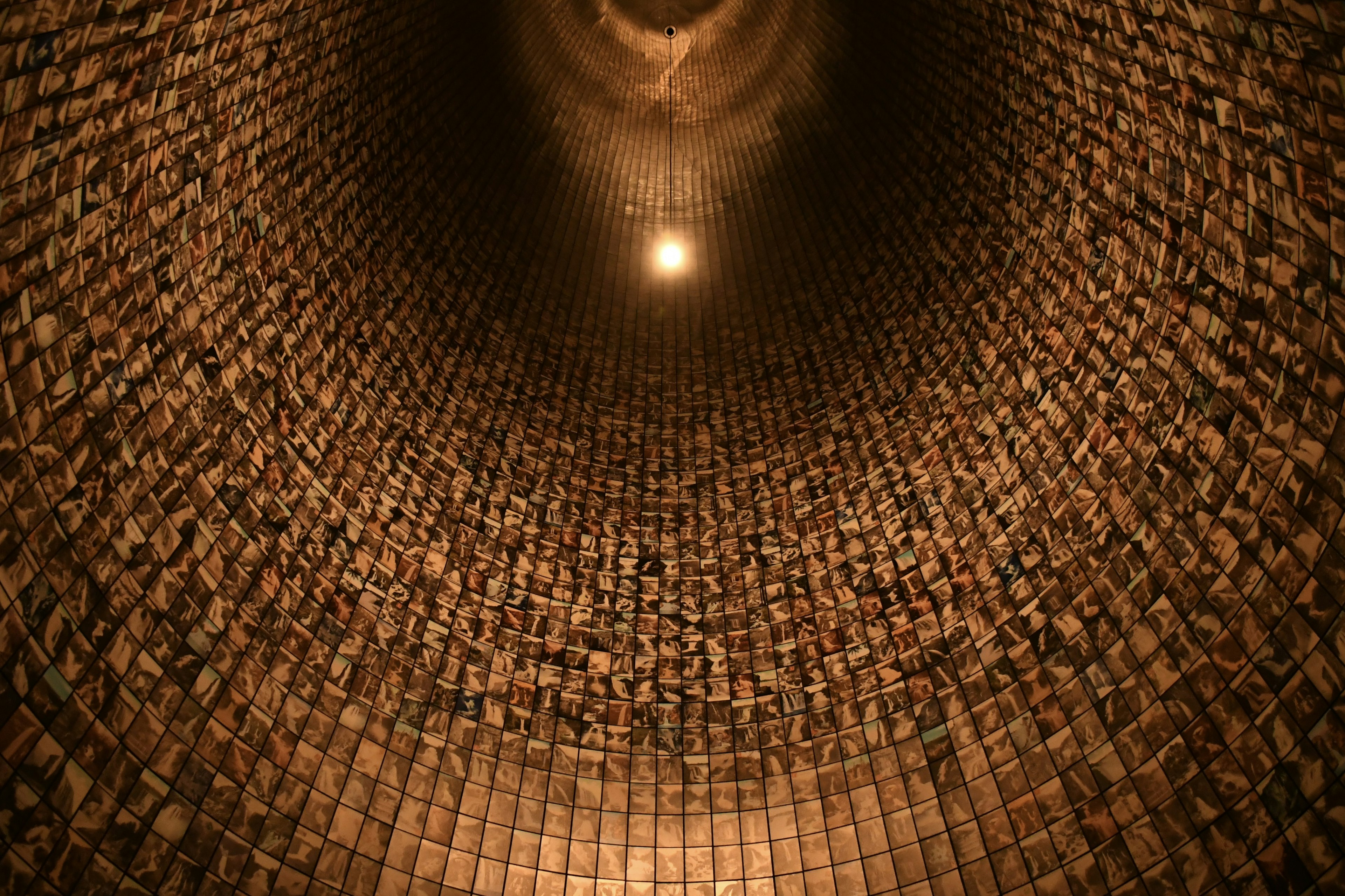 Vue vers le haut à l'intérieur d'une structure cylindrique avec des murs en briques et une source de lumière en haut