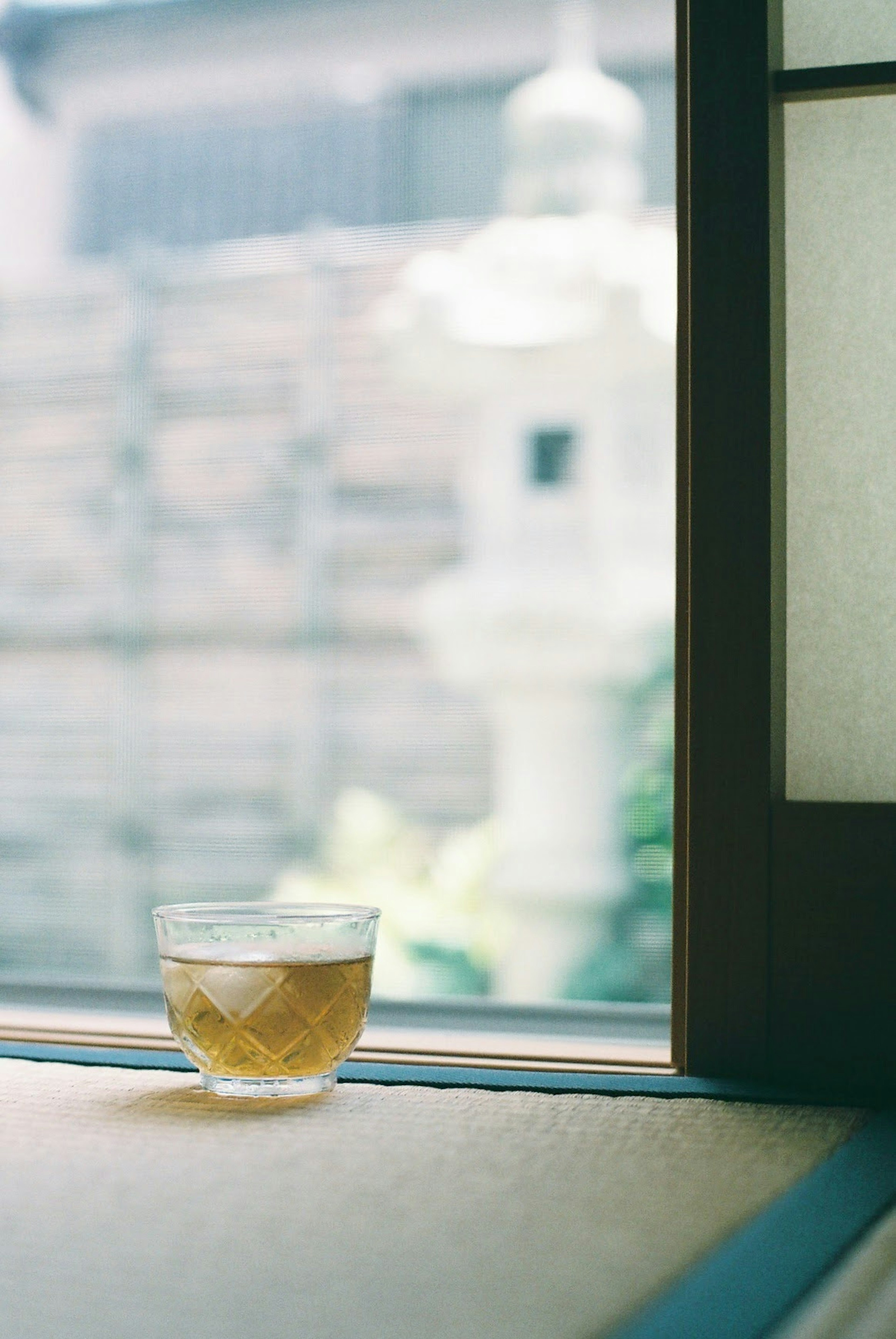 A glass of tea on a windowsill with a blurred outdoor background