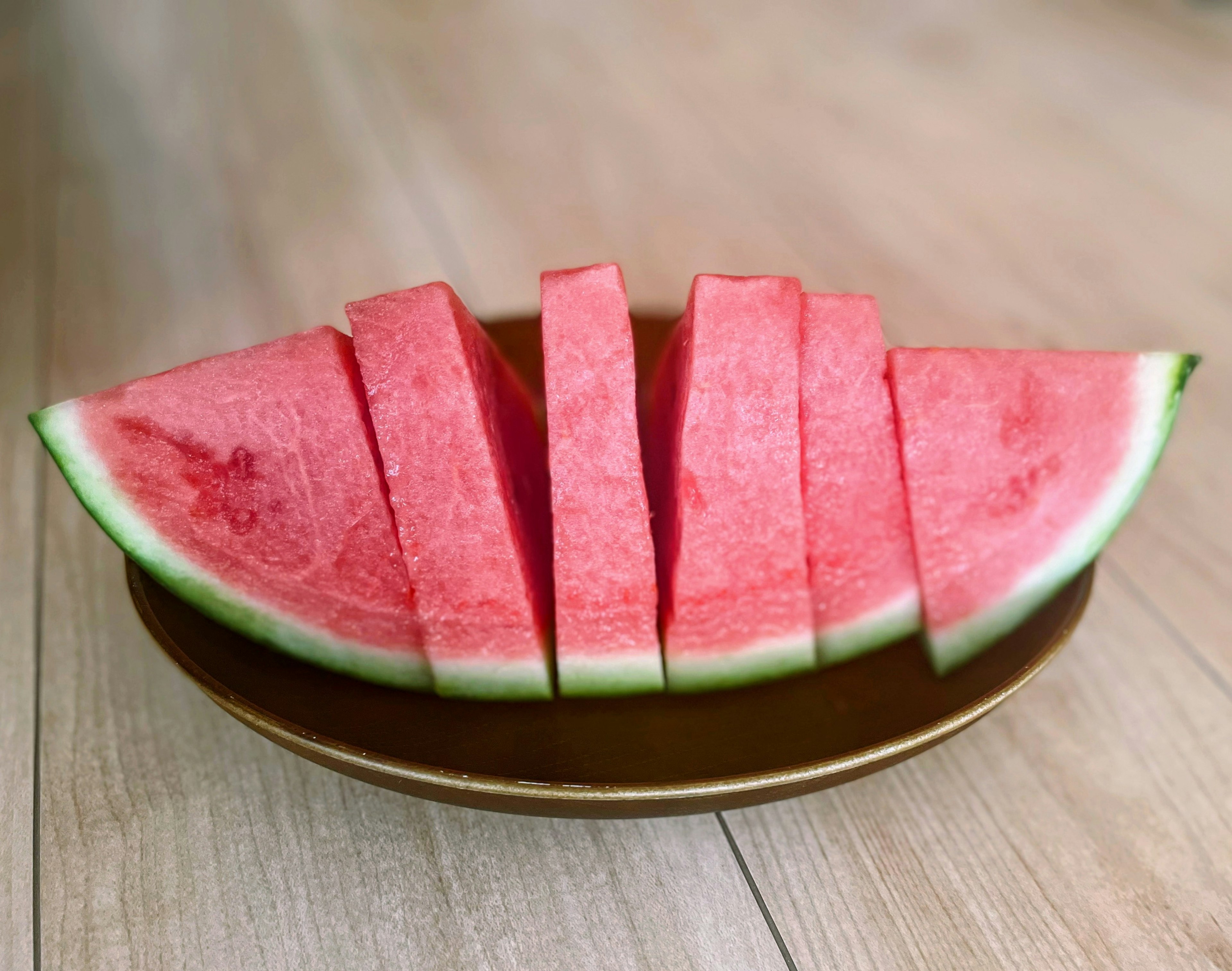 Sliced watermelon arranged on a brown plate