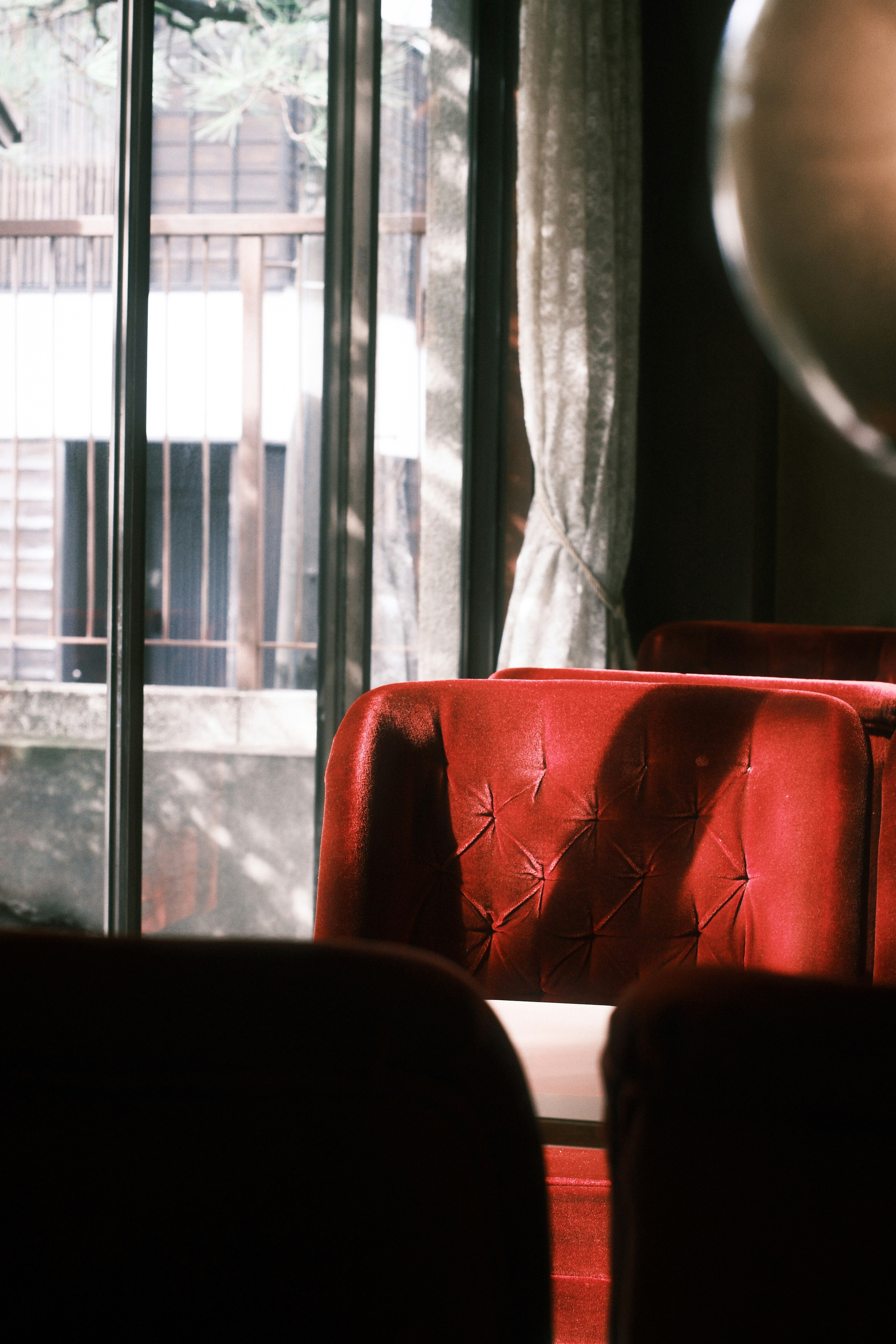 Une scène intérieure simple avec une chaise rouge et de la lumière passant par une fenêtre