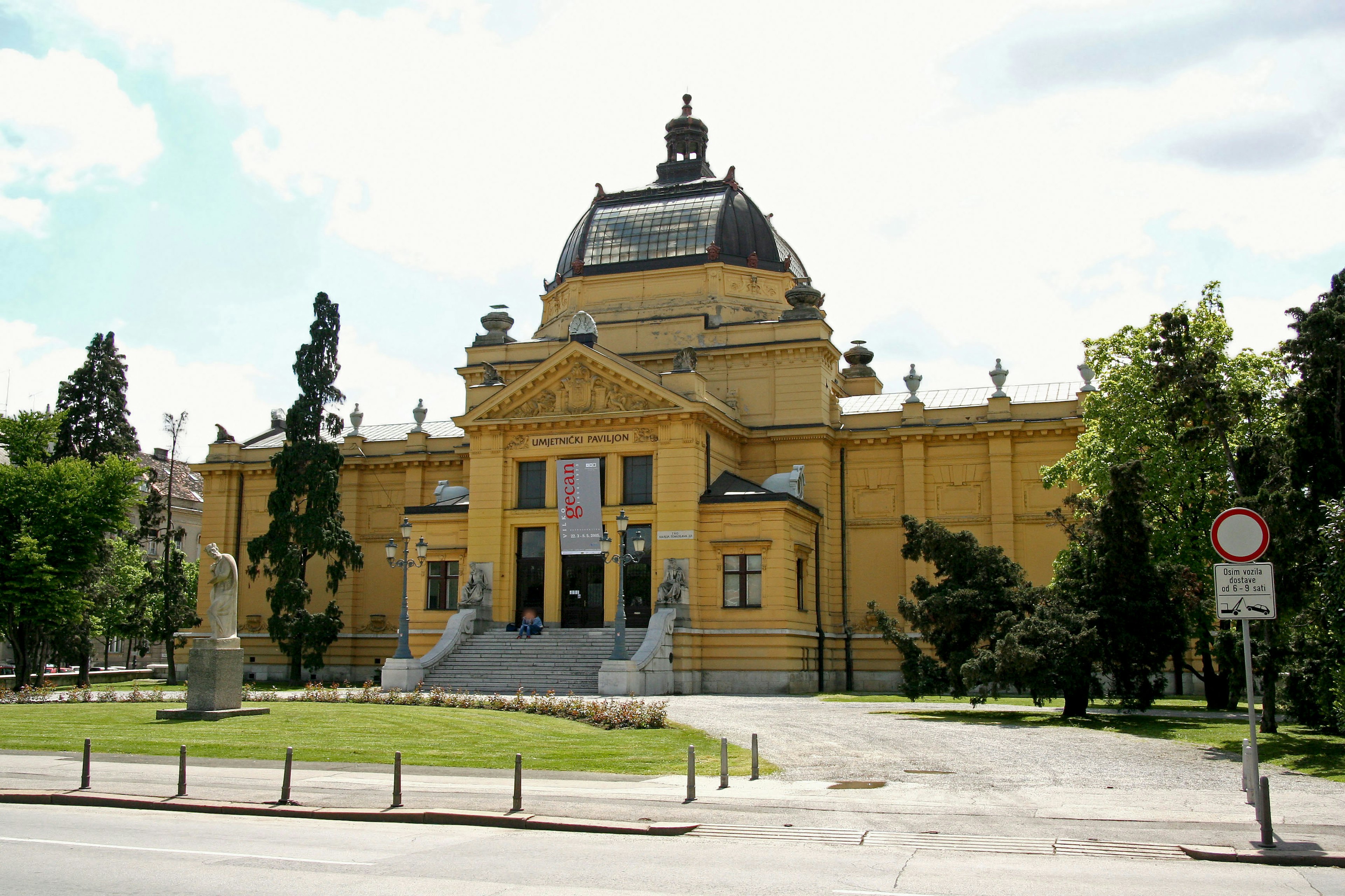 Vista exterior de un museo de arte amarillo rodeado de árboles verdes