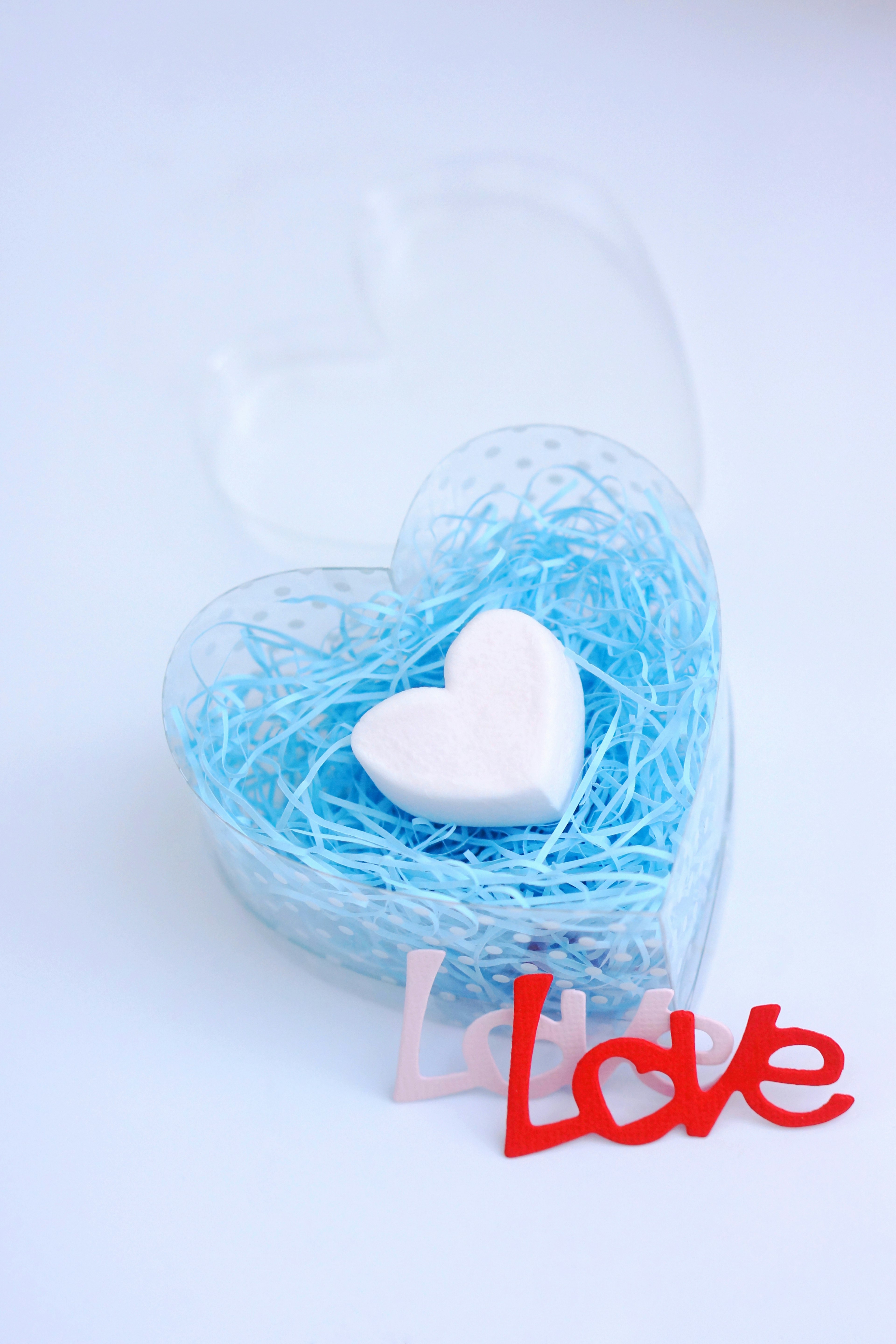 Macarón en forma de corazón blanco en paja azul con texto rojo Love