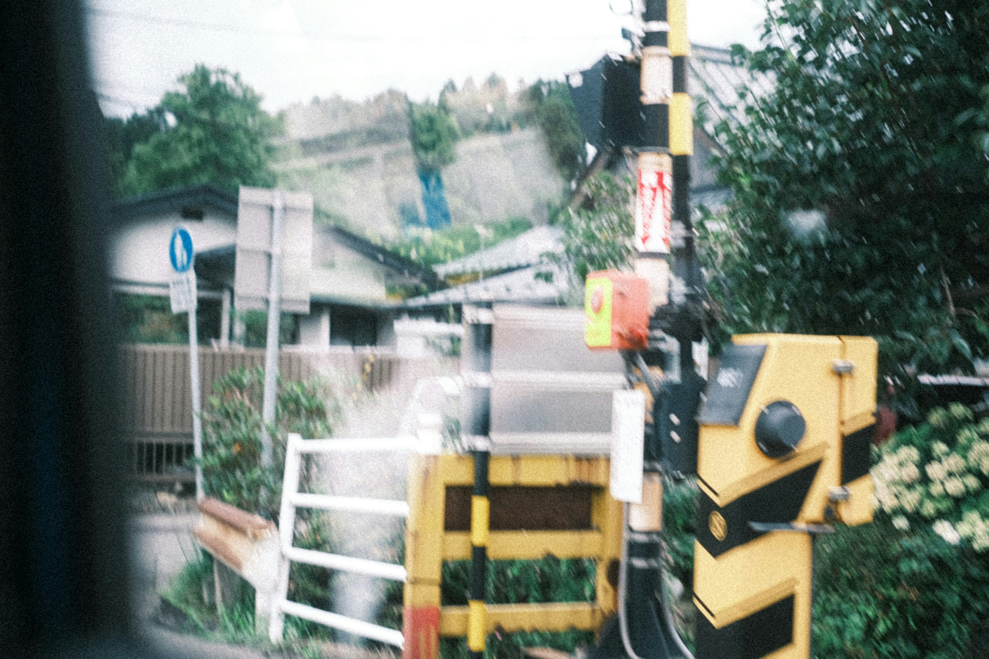 Yellow and black signal post with nearby houses in a scenic setting