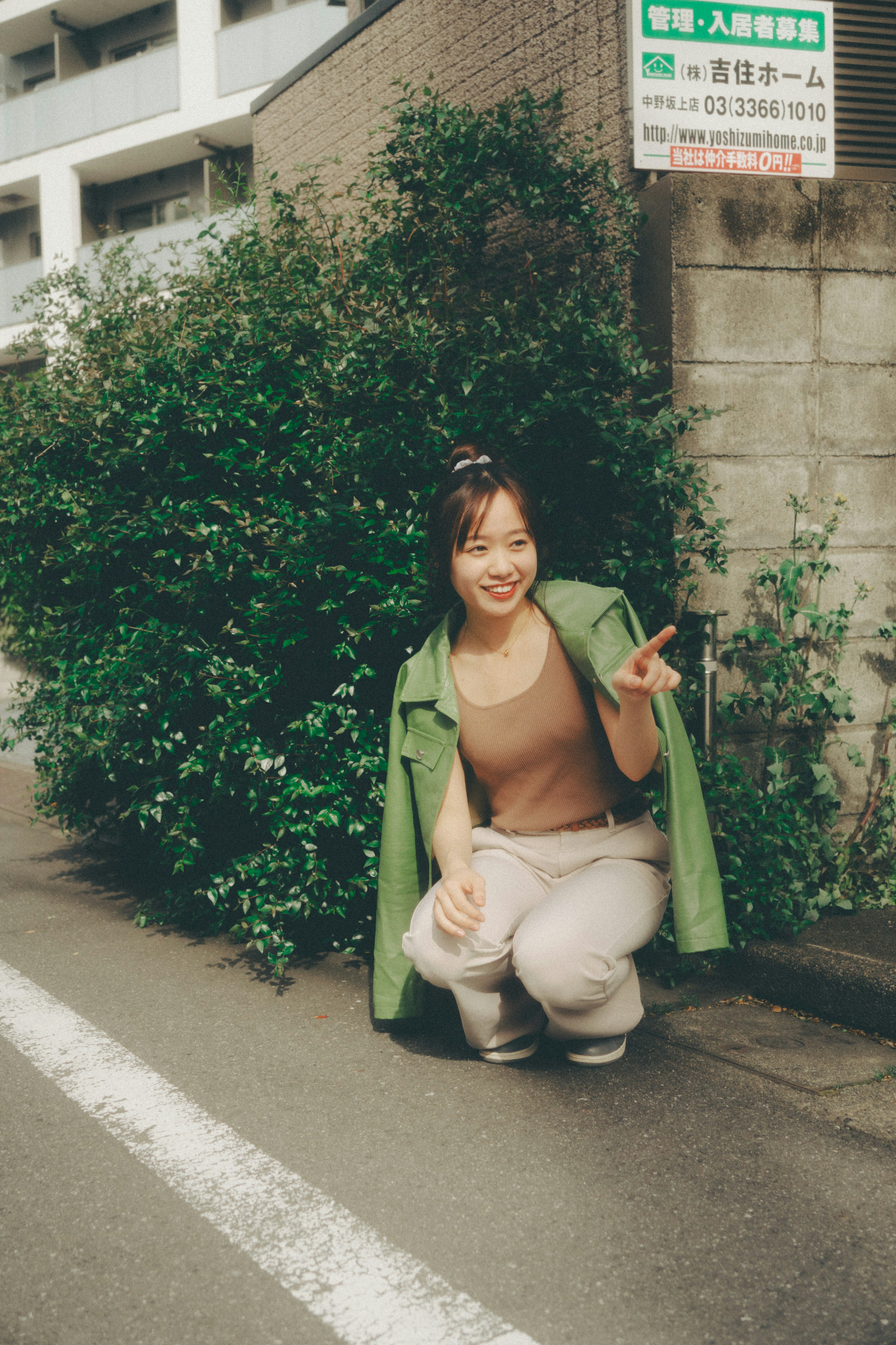 A woman in a green coat posing on a street corner