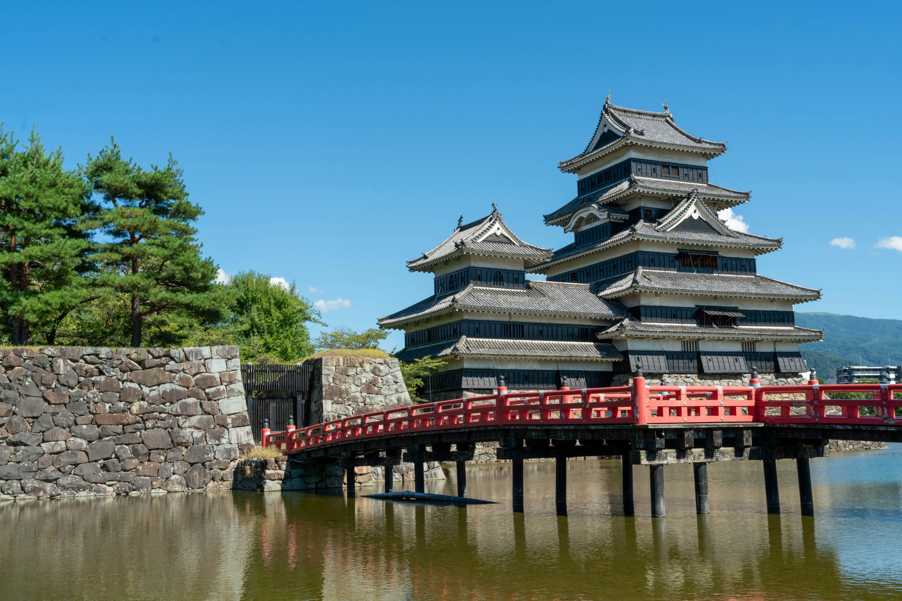 Castillo de Matsumoto con un puente rojo reflejándose en el agua