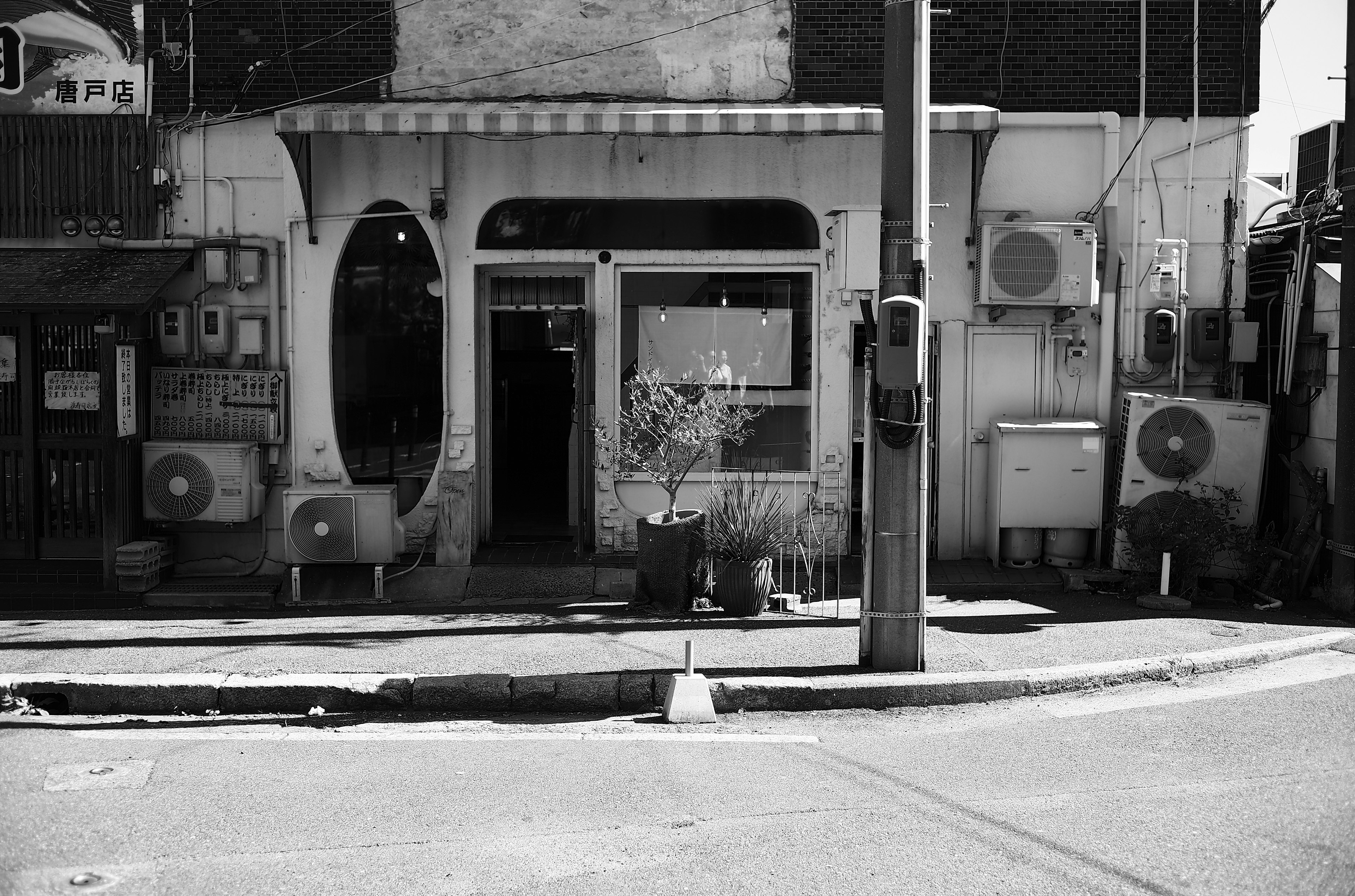 Black and white exterior of a shop featuring vintage architectural design and multiple air conditioning units