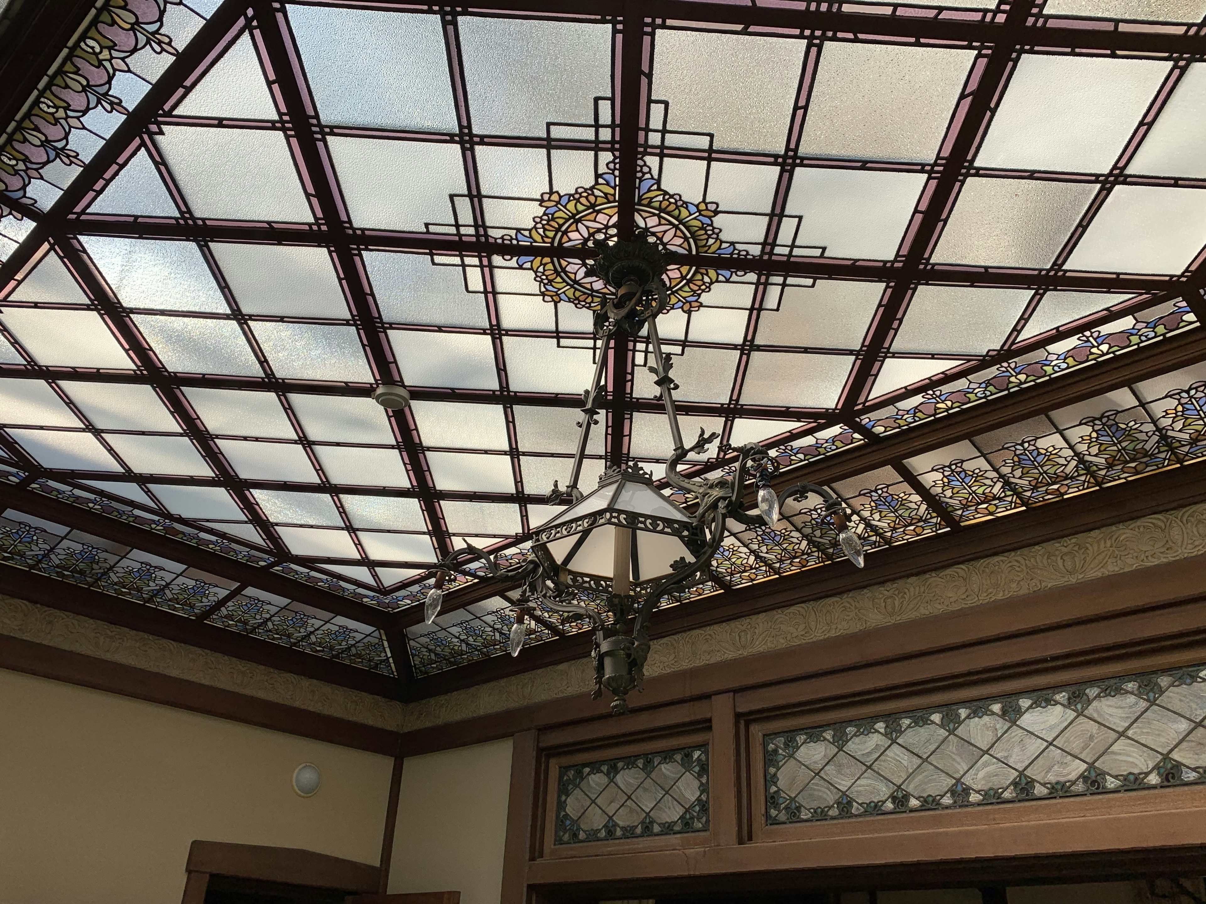 Interior photo featuring a beautiful stained glass ceiling and chandelier