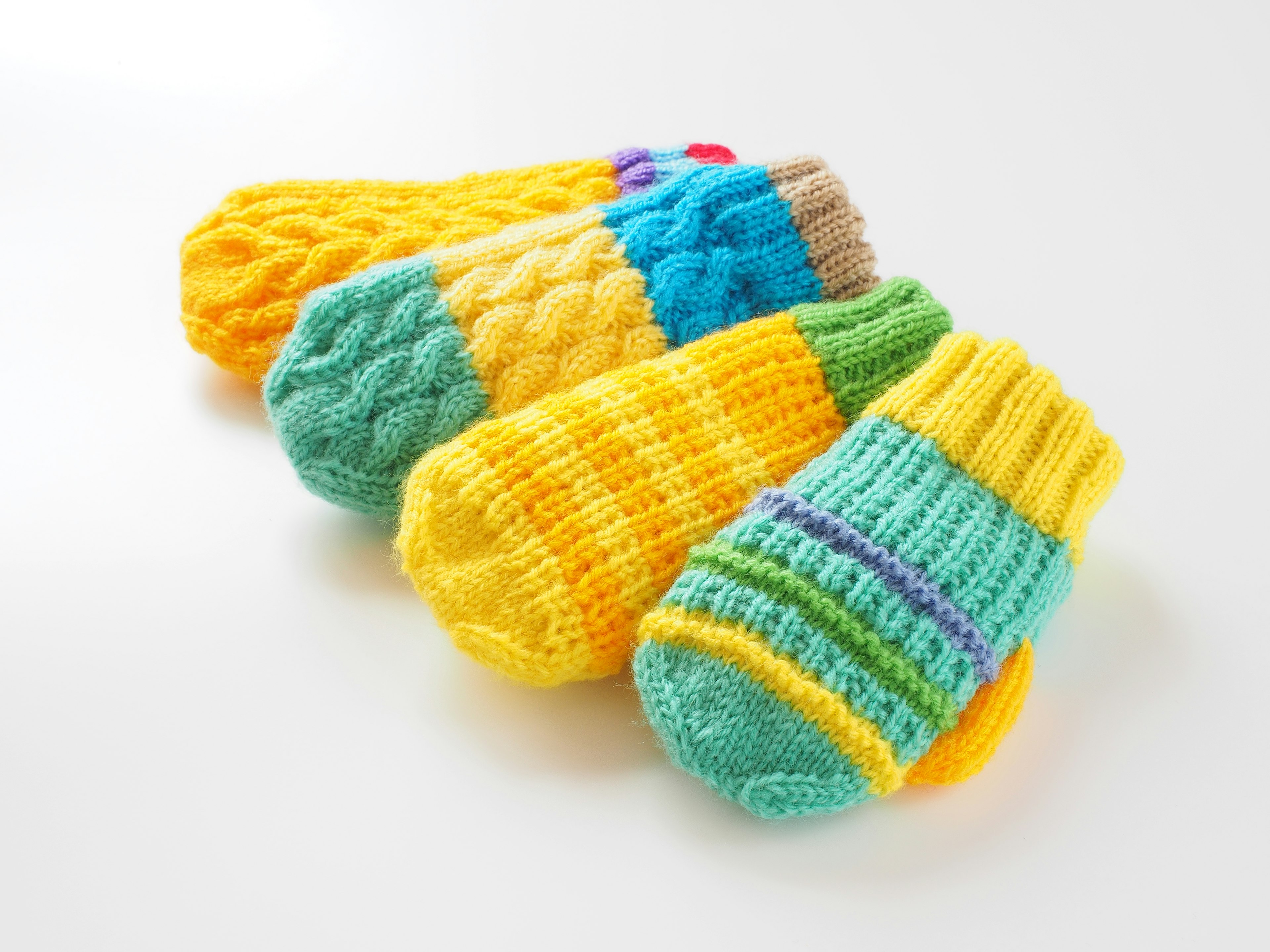 A collection of four colorful knitted mittens featuring yellow and blue hues