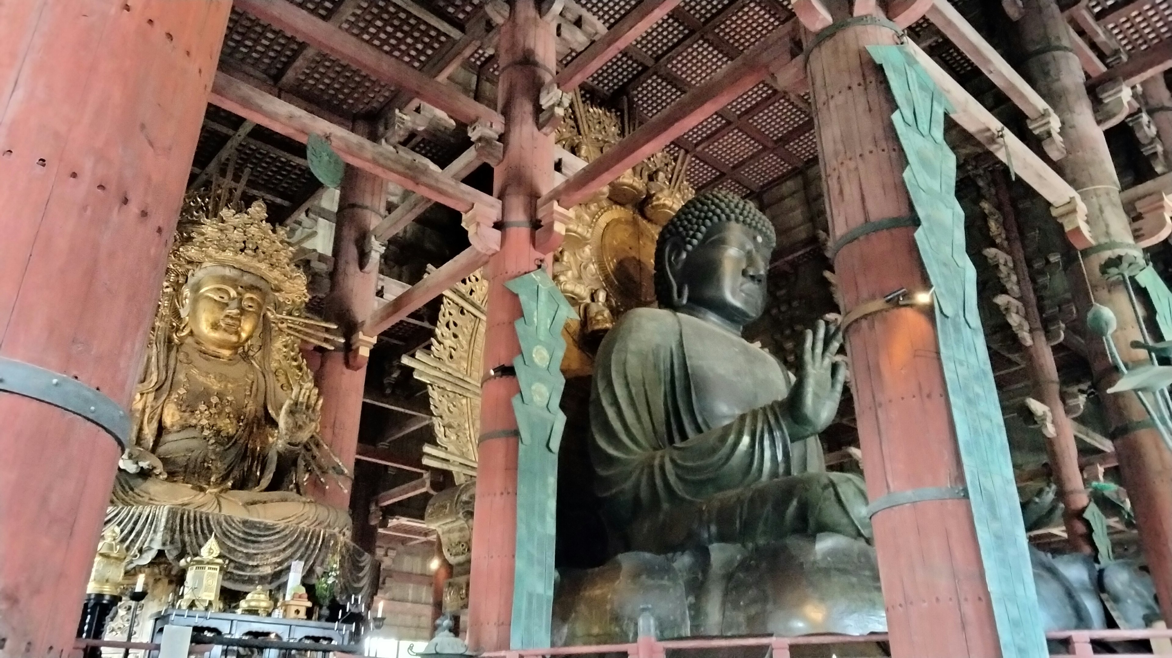 Vista interna di un tempio con una grande statua del Buddha e una figura di Kannon