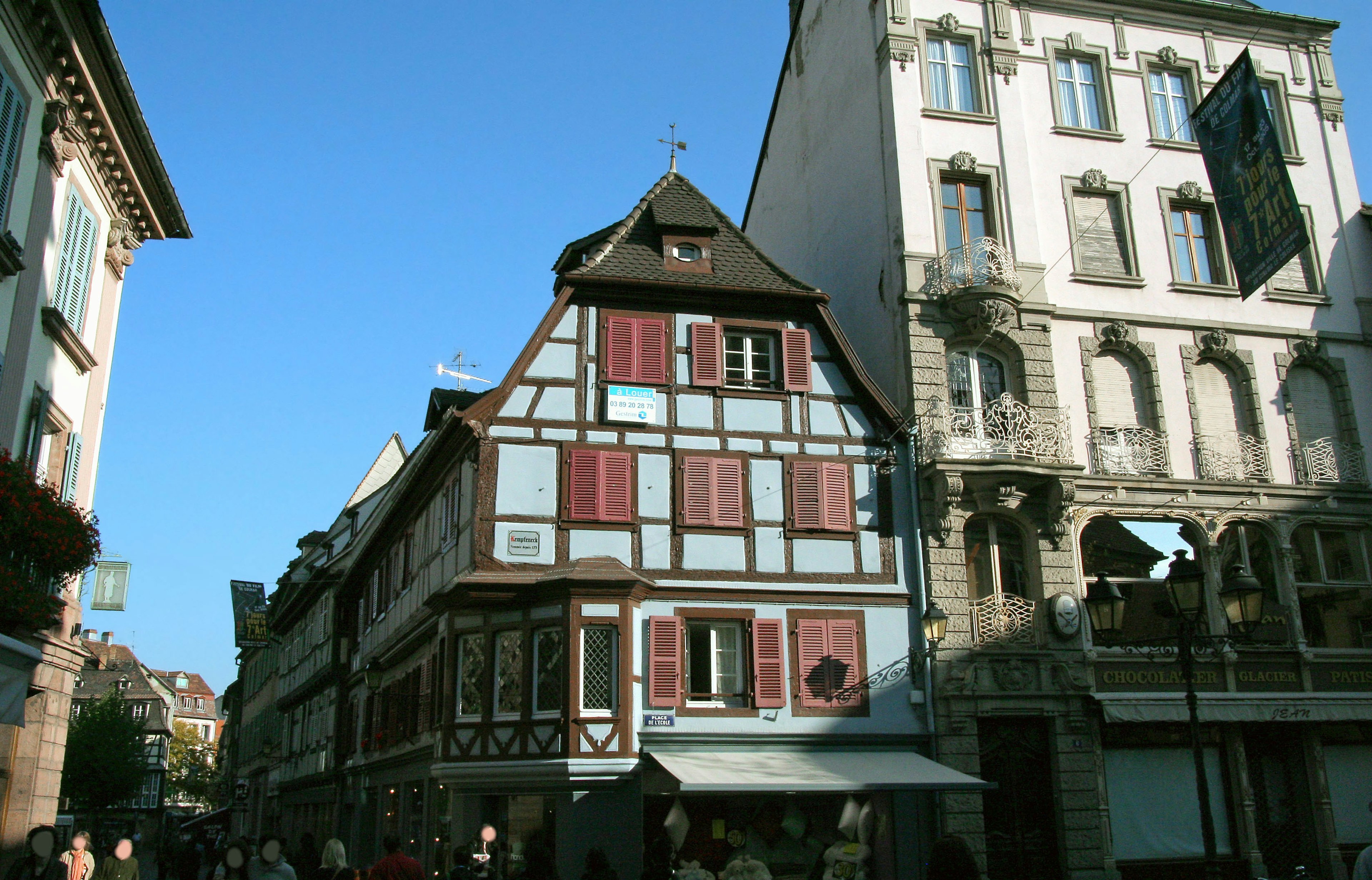 Traditional timber-framed house under blue sky with modern building