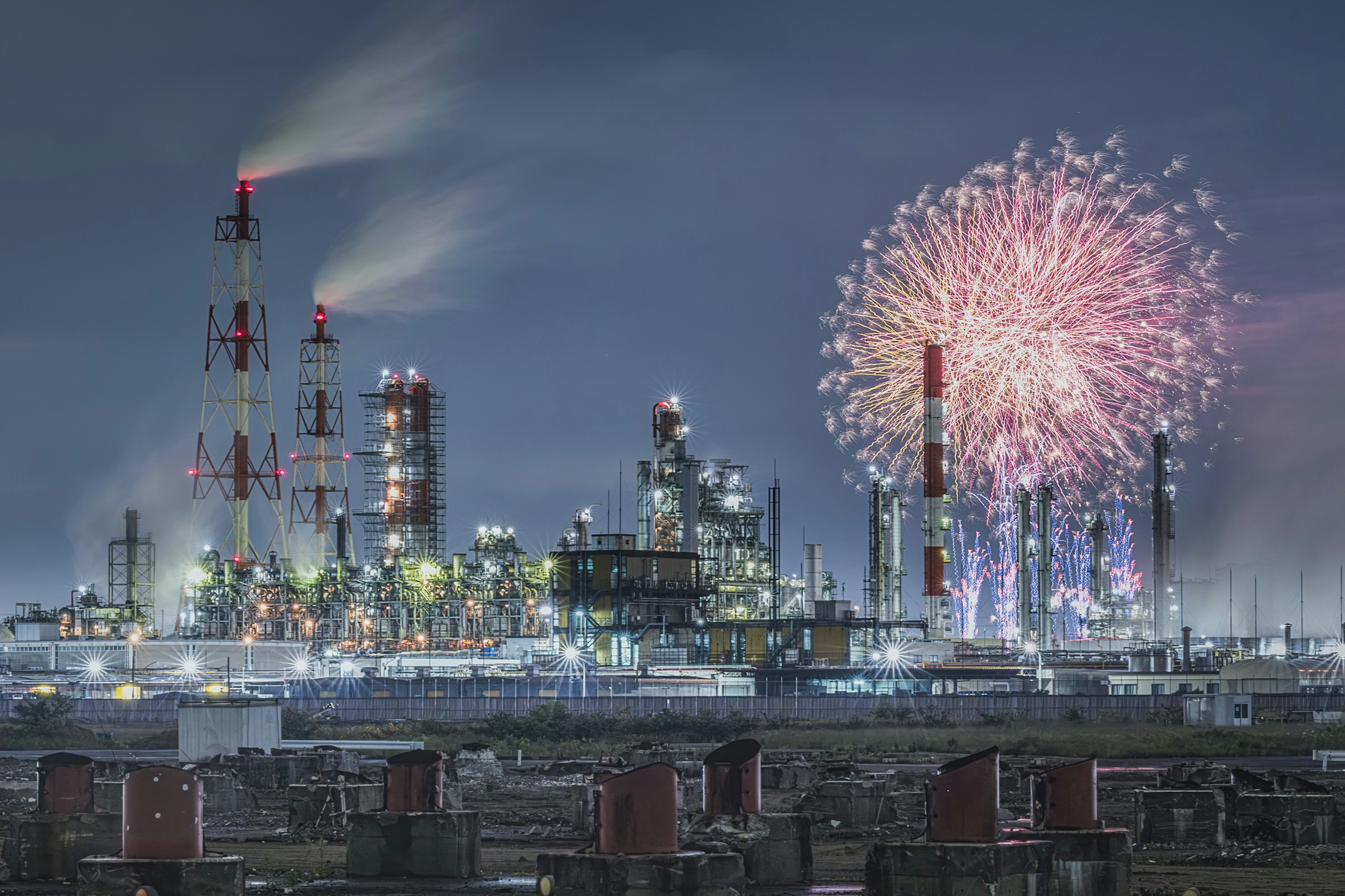 夜の工業地帯に花火が映える工場の風景