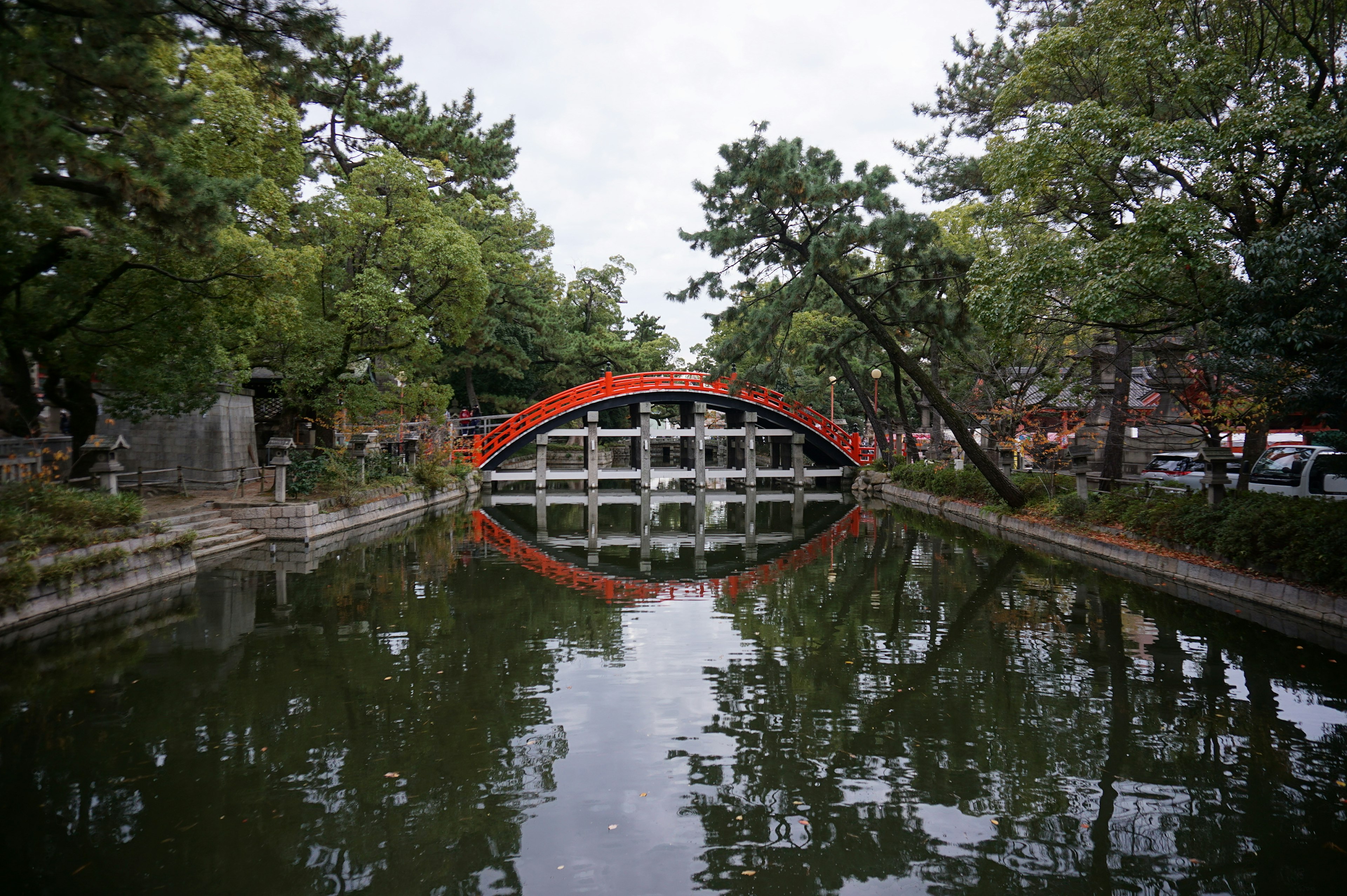 Puente en arco rojo sobre un estanque tranquilo rodeado de árboles