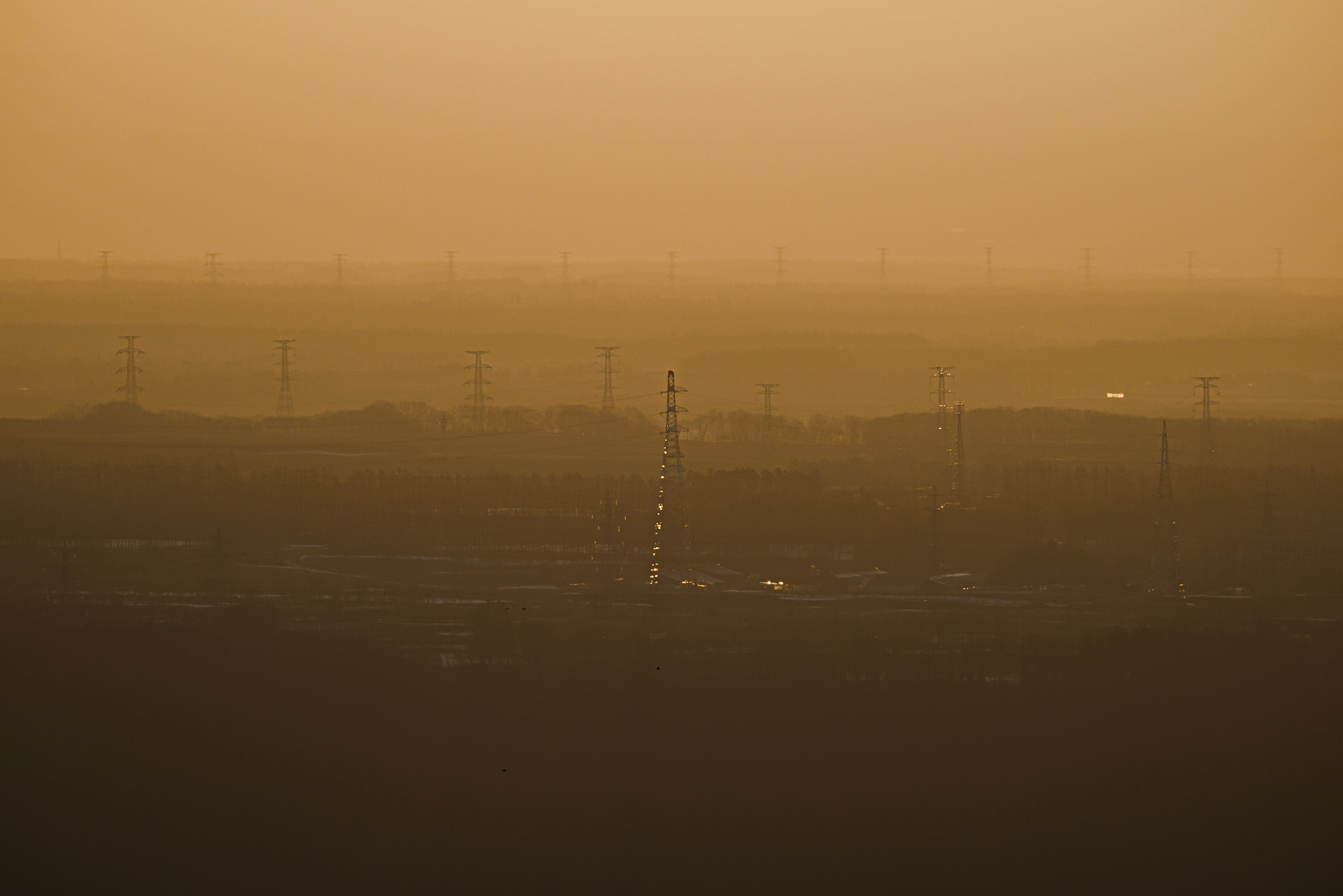 Silhouetted power lines against a golden haze at sunset