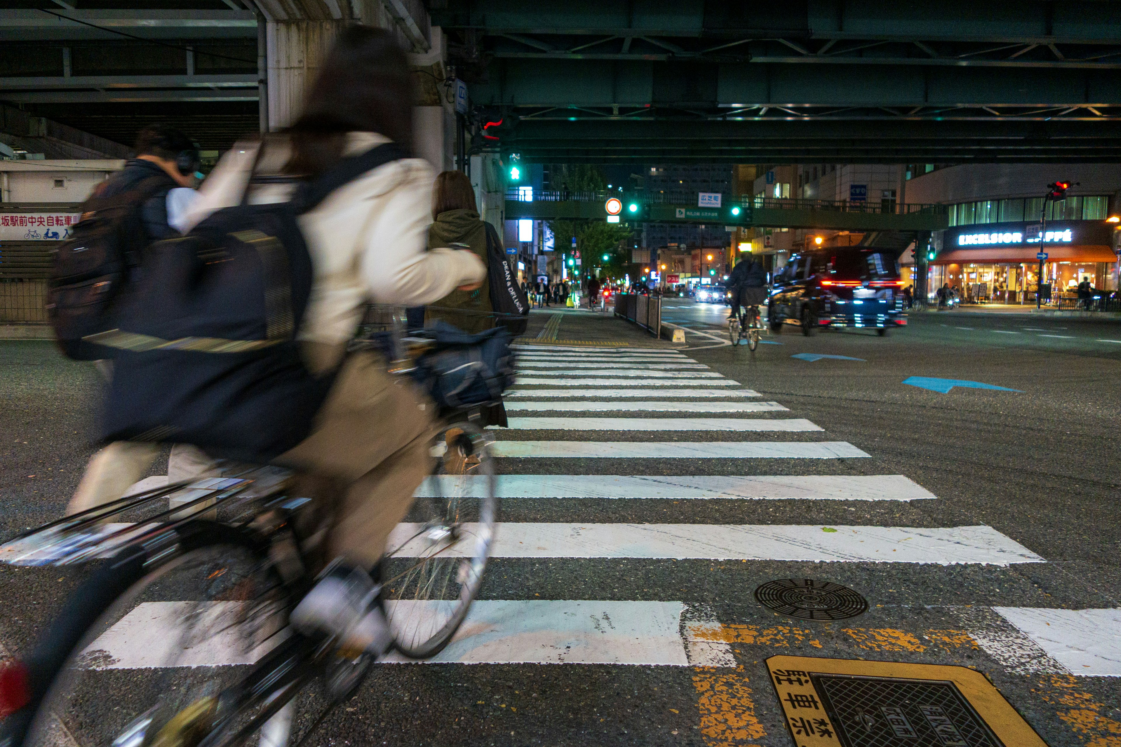 A person riding a bicycle across a crosswalk at night with traffic lights