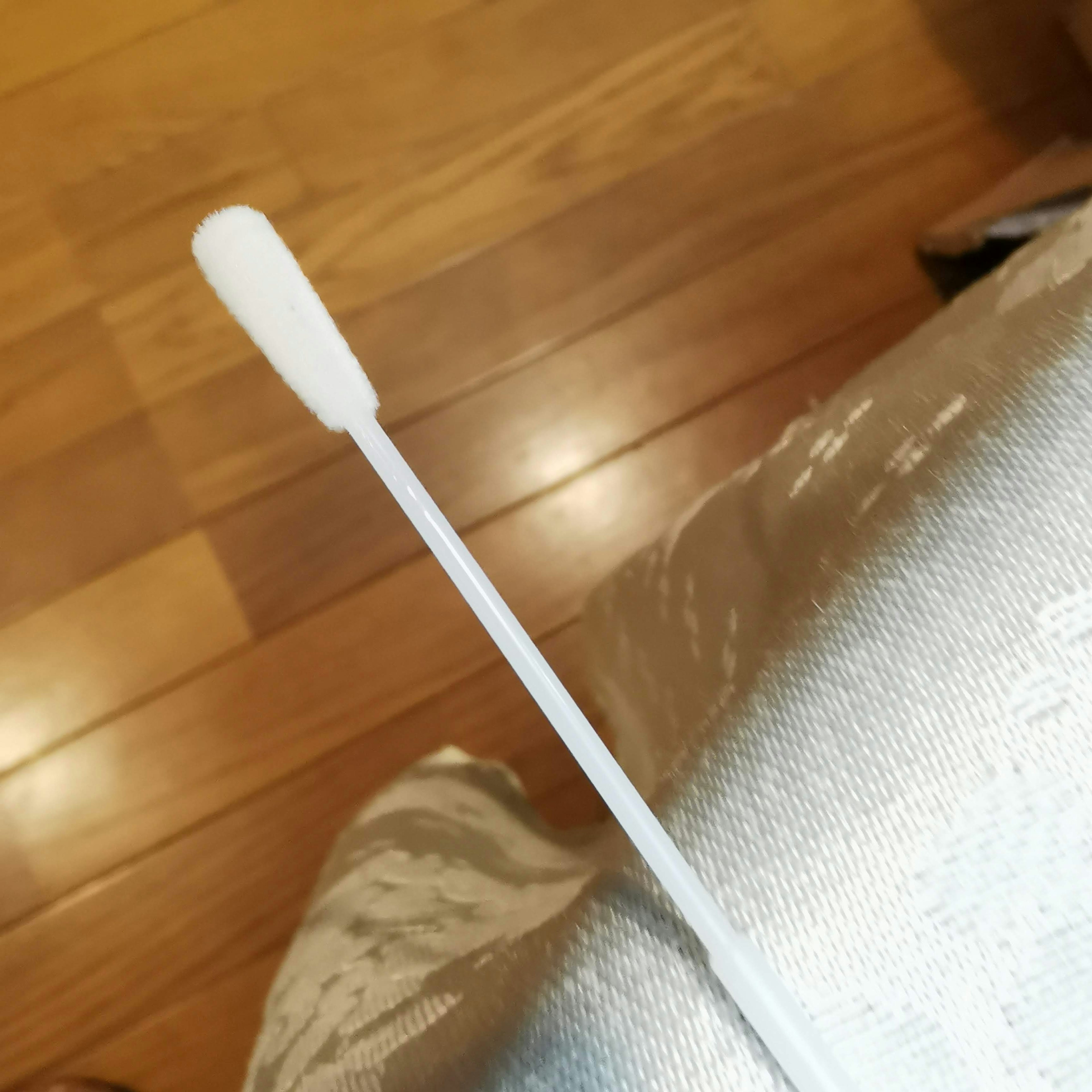 A white cotton swab placed on a wooden floor