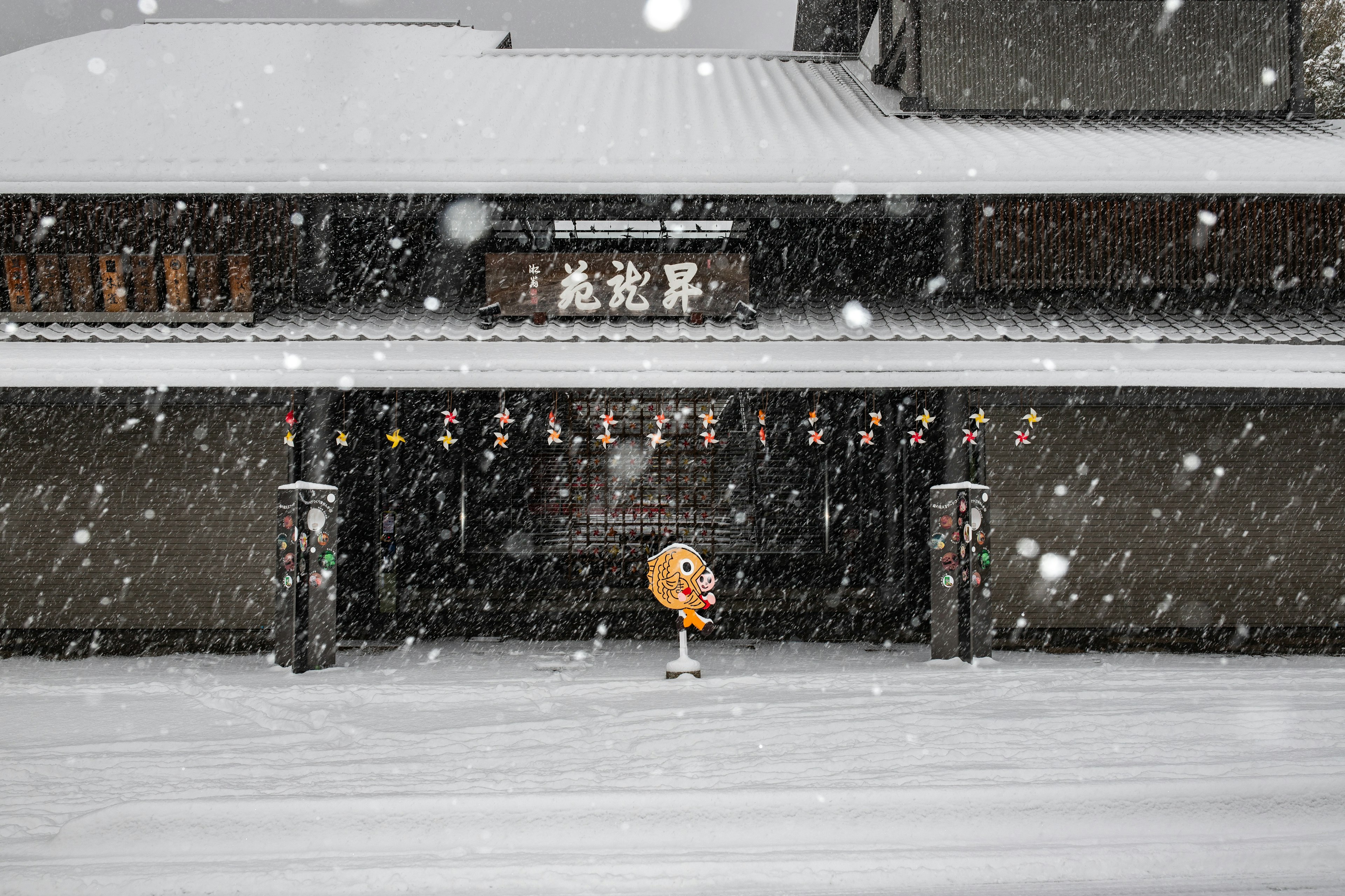 雪中站立的橙色玩偶和背景中的传统建筑