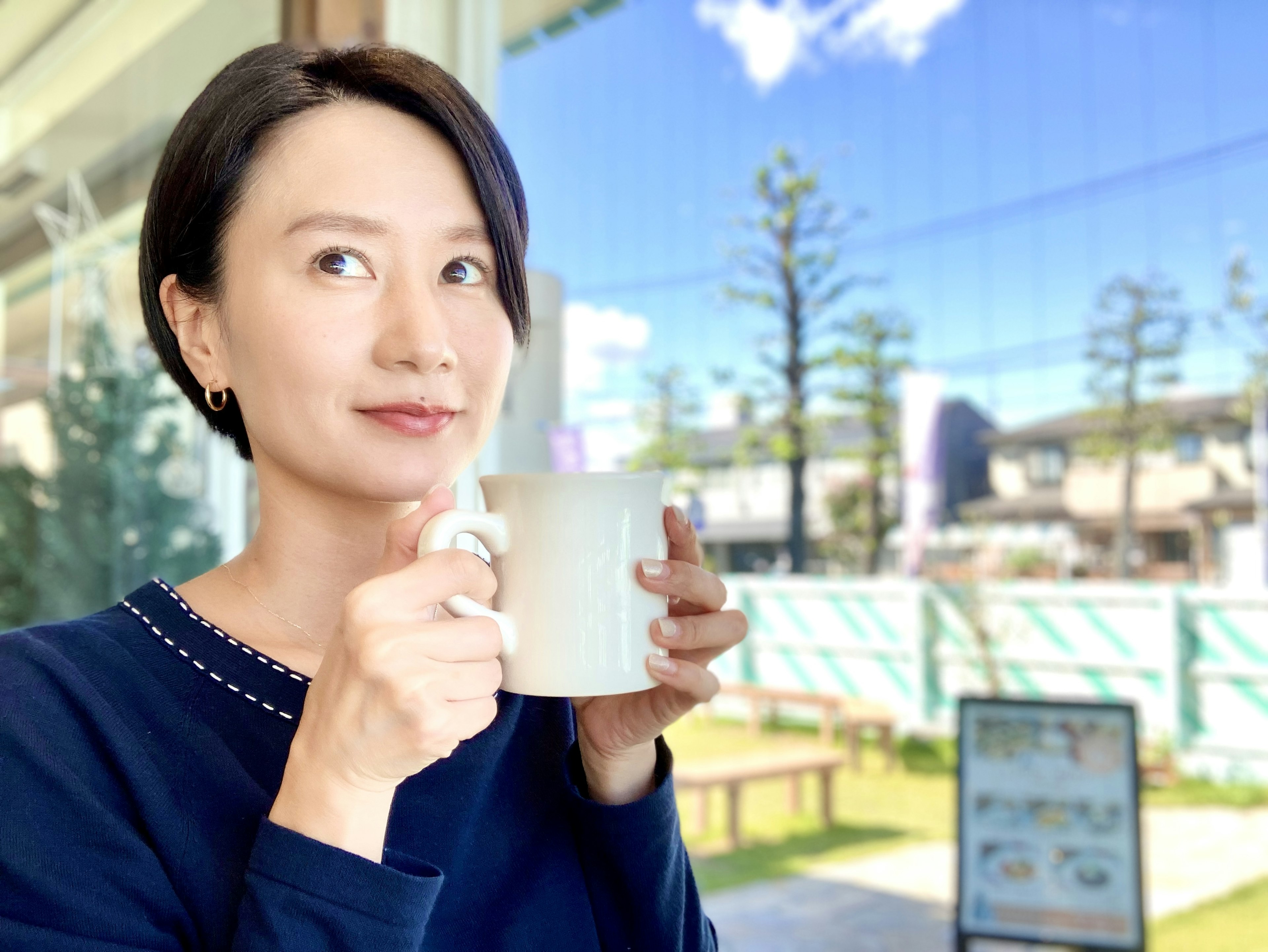 女性がカフェでコーヒーを持ちながら微笑んでいる