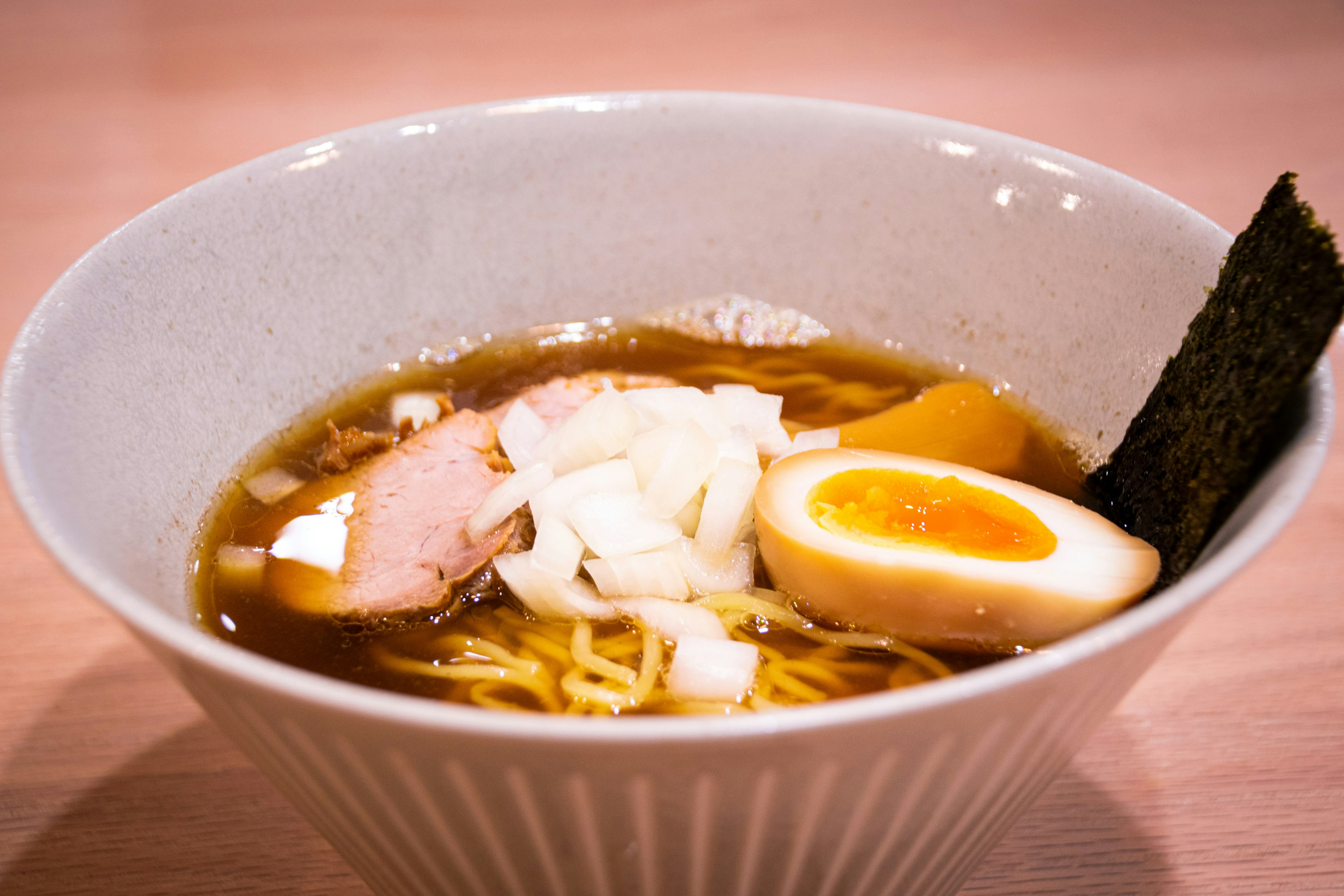 A delicious bowl of ramen featuring slices of chashu, soft-boiled egg, green onions, and nori