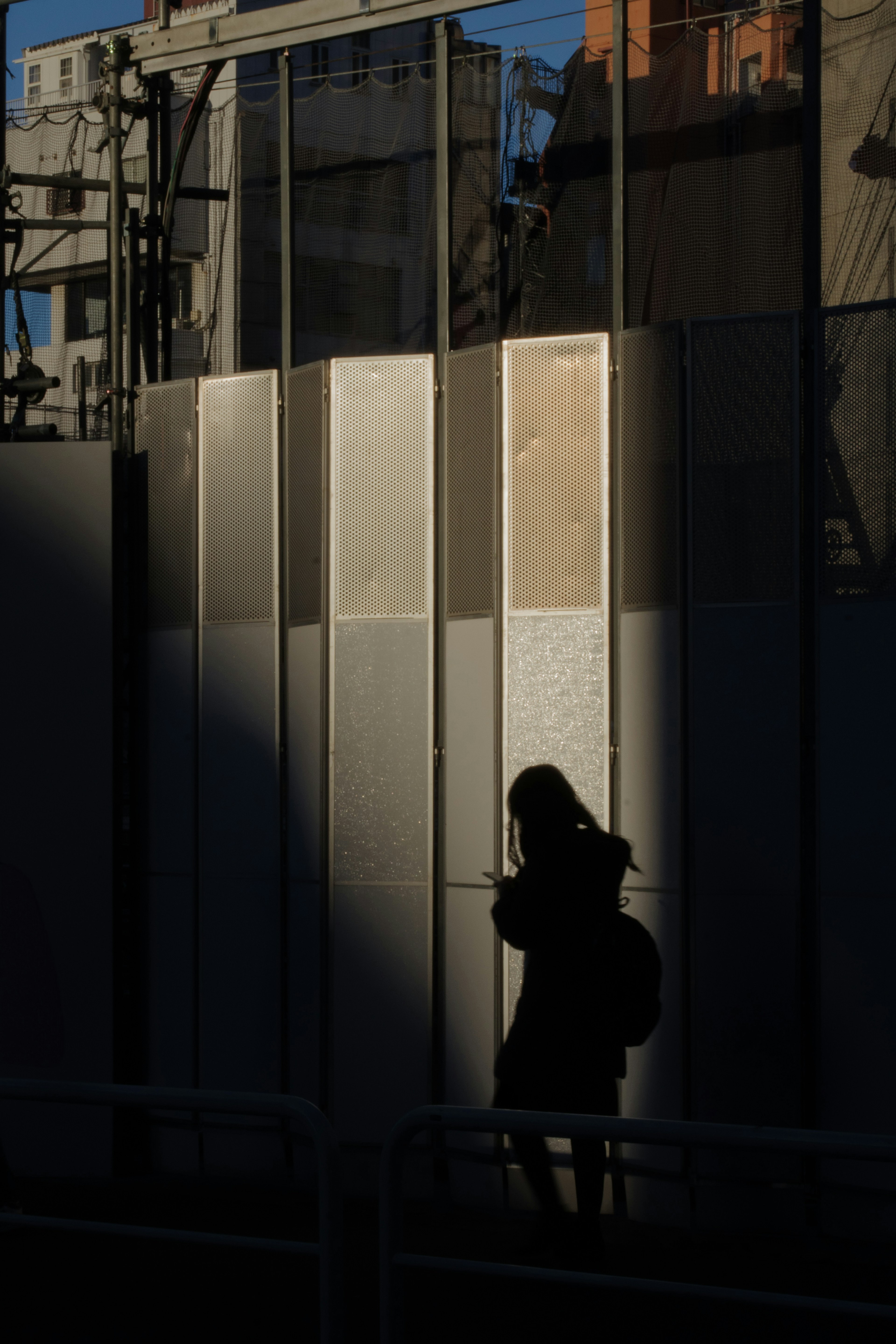 Silhouette einer Frau, die vor Glasschalen mit Schatten steht